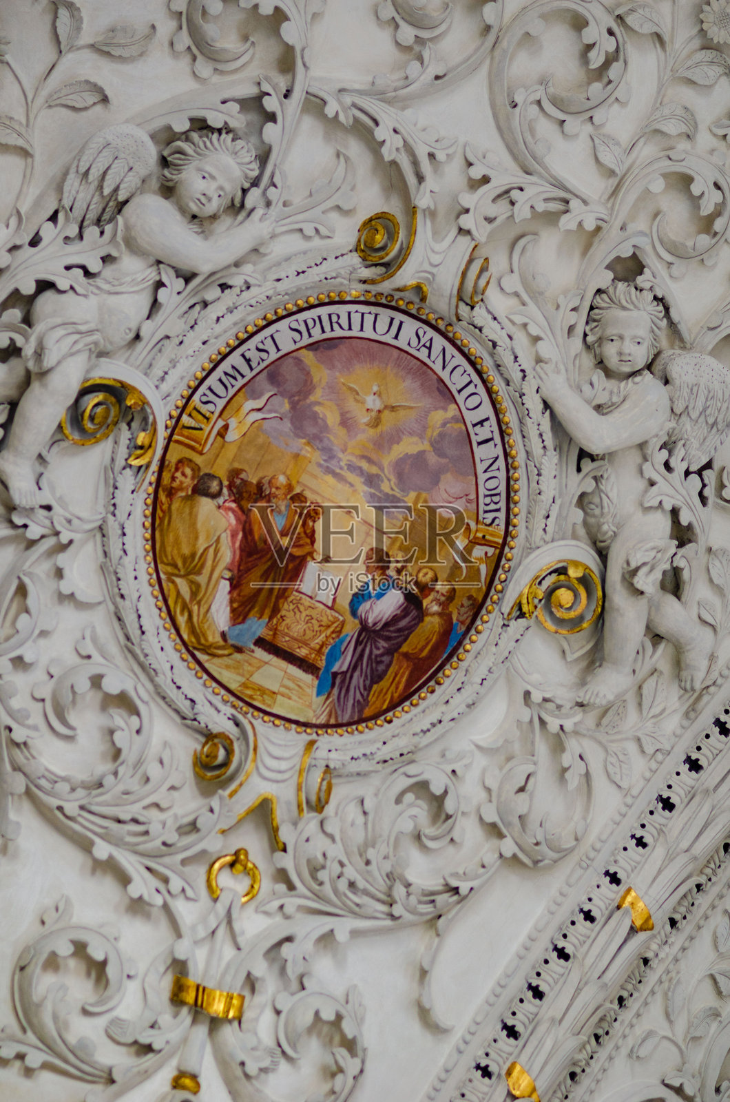 巴洛克风格教堂的内部，装饰华丽的拱形天花板上绘有描绘宗教场景和符号的壁画和雕塑，顶部有高拱窗户透入光线。照片摄影图片