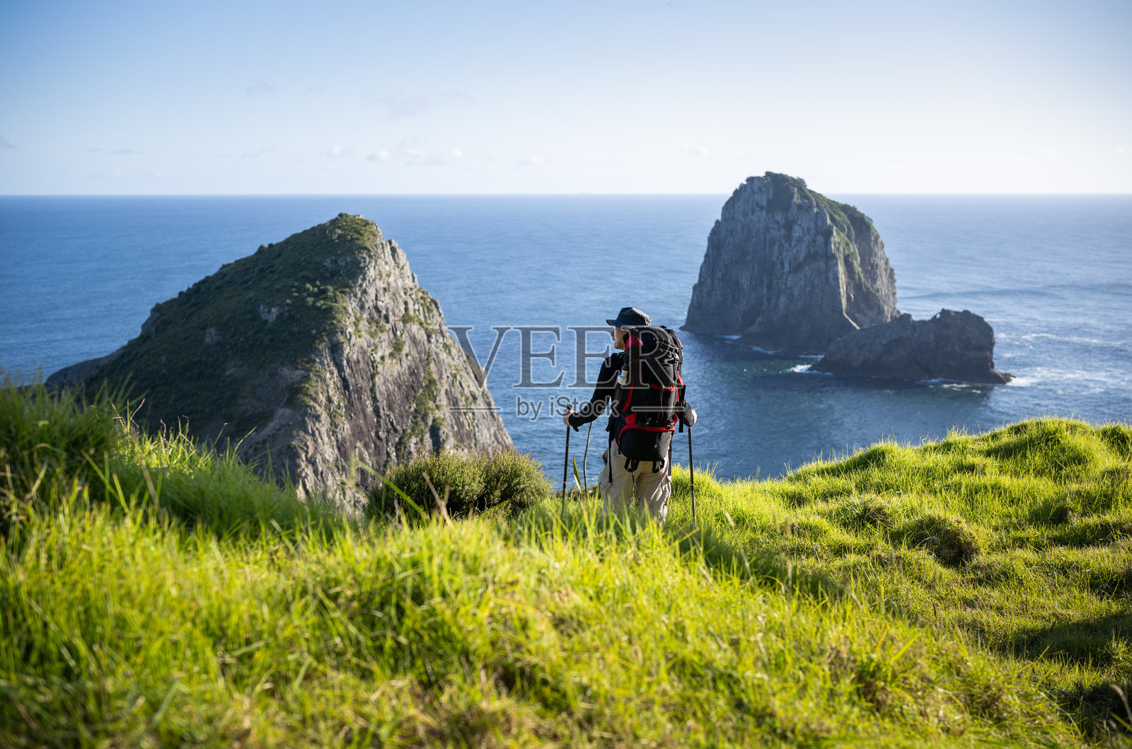 背包客在凯普布雷特步道上徒步旅行。远处是有“岩洞”的岛屿。岛屿湾。照片摄影图片