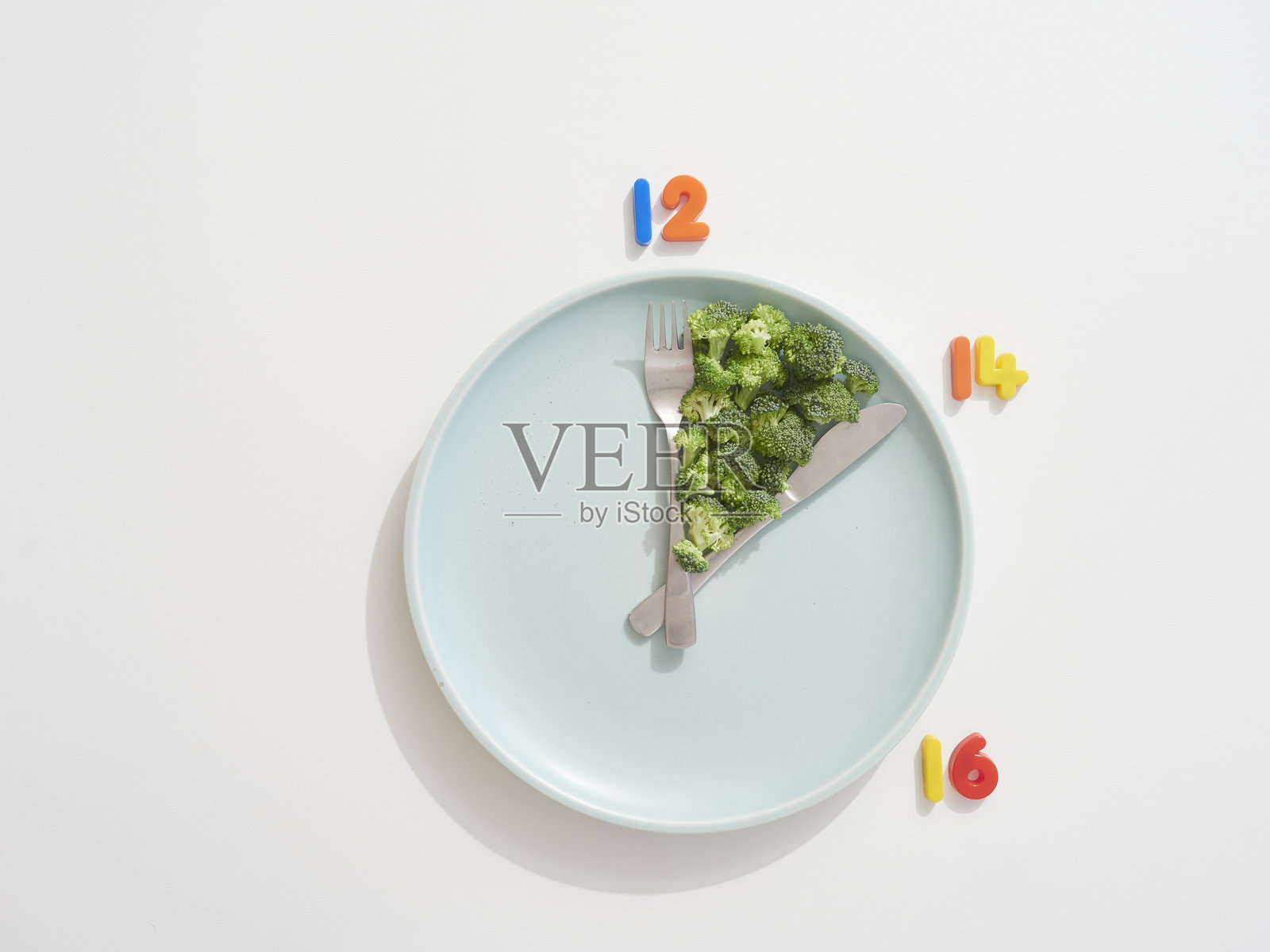 间歇性禁食概念，时钟盘子上的西兰花照片摄影图片