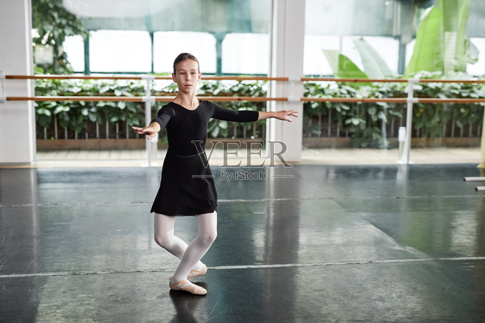 年轻的芭蕾舞者穿着裙子在工作室里与植物一起表演旋转舞。照片摄影图片