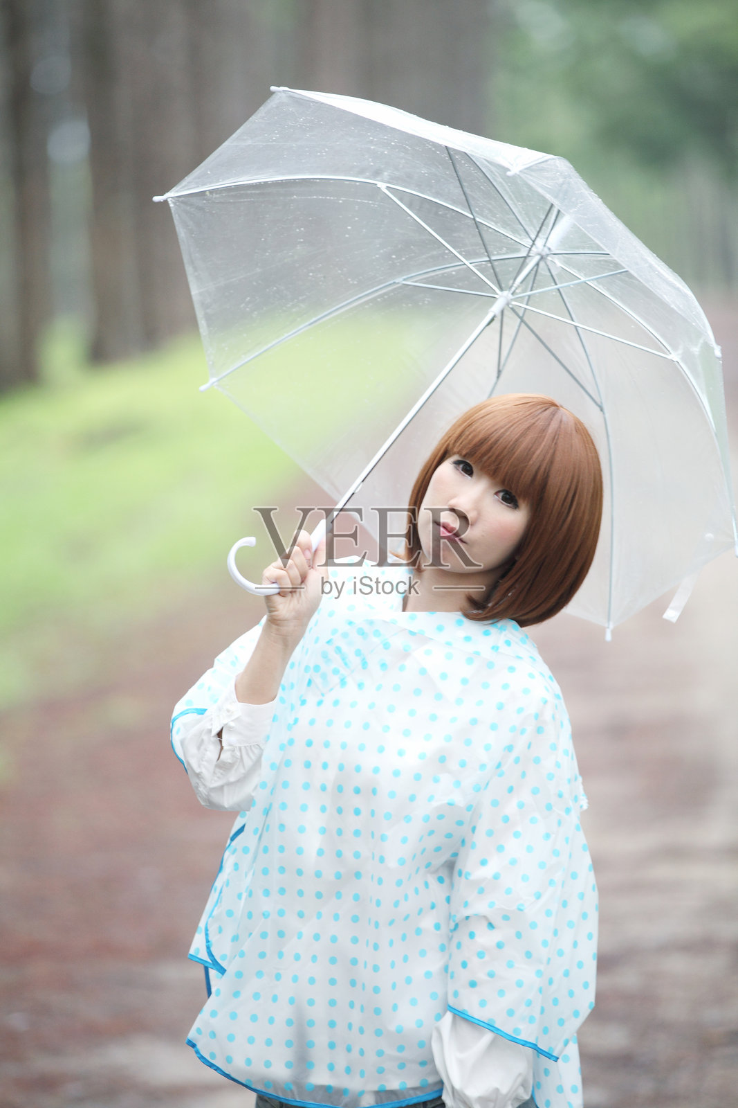 在雨季的泥土路上，手持雨伞的女性肖像照片摄影图片