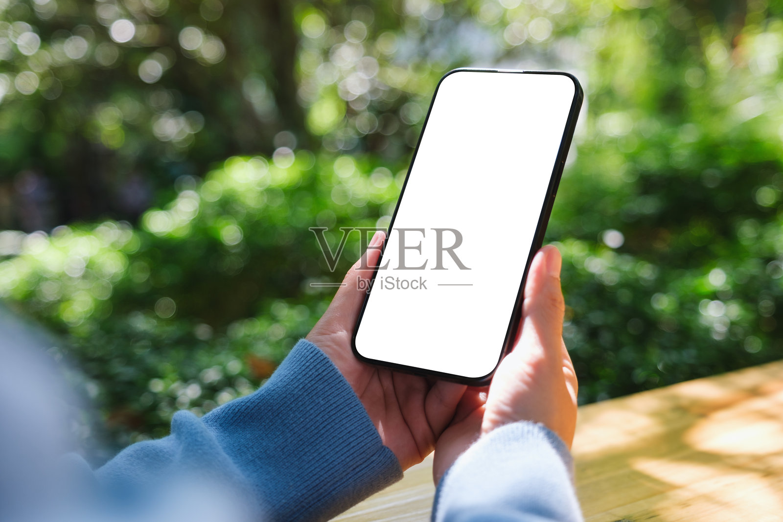 一位女性在户外手持手机，背景是空白的白色桌面屏幕的模型图。照片摄影图片