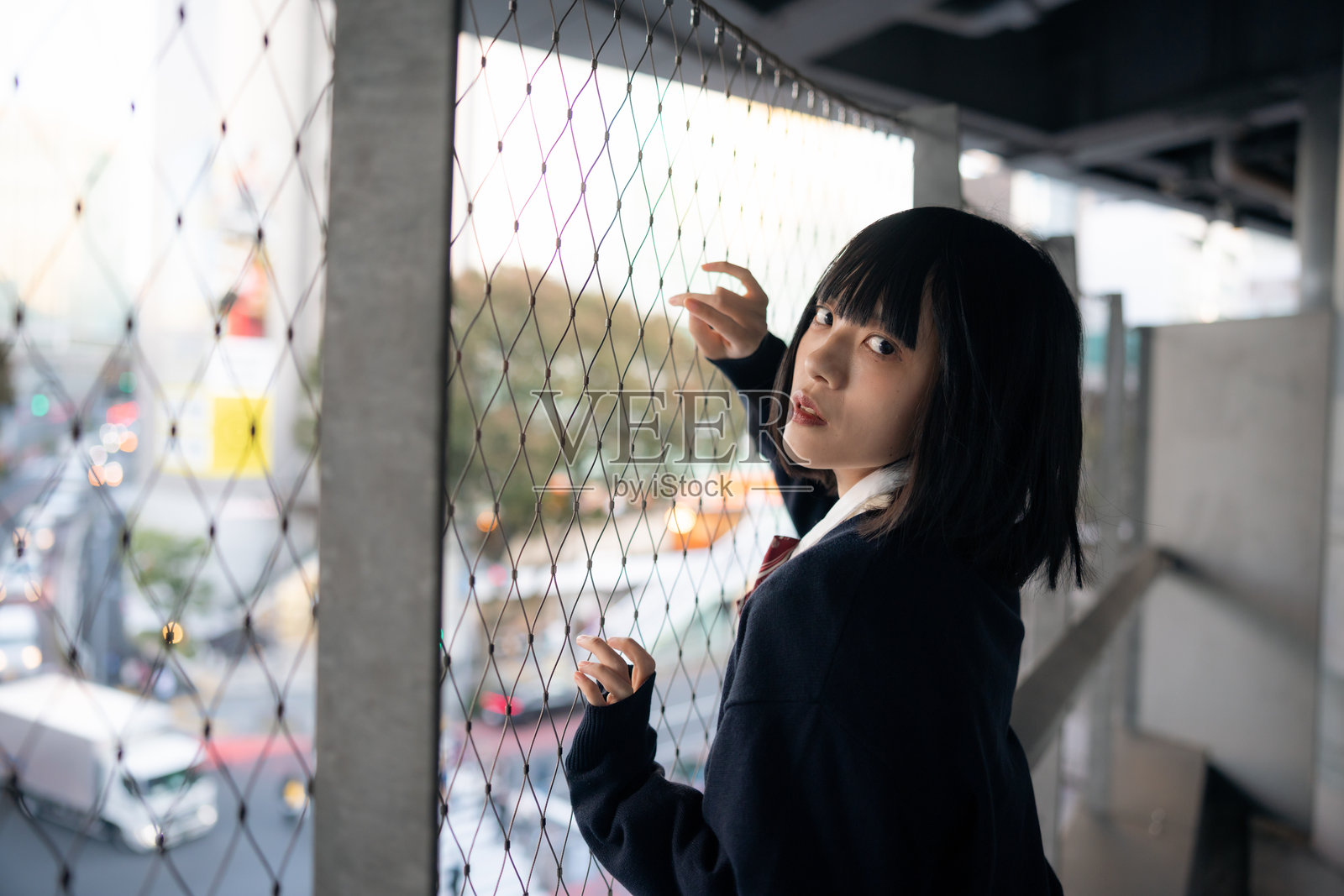 穿着校服的女性倚靠在城市围栏上。照片摄影图片