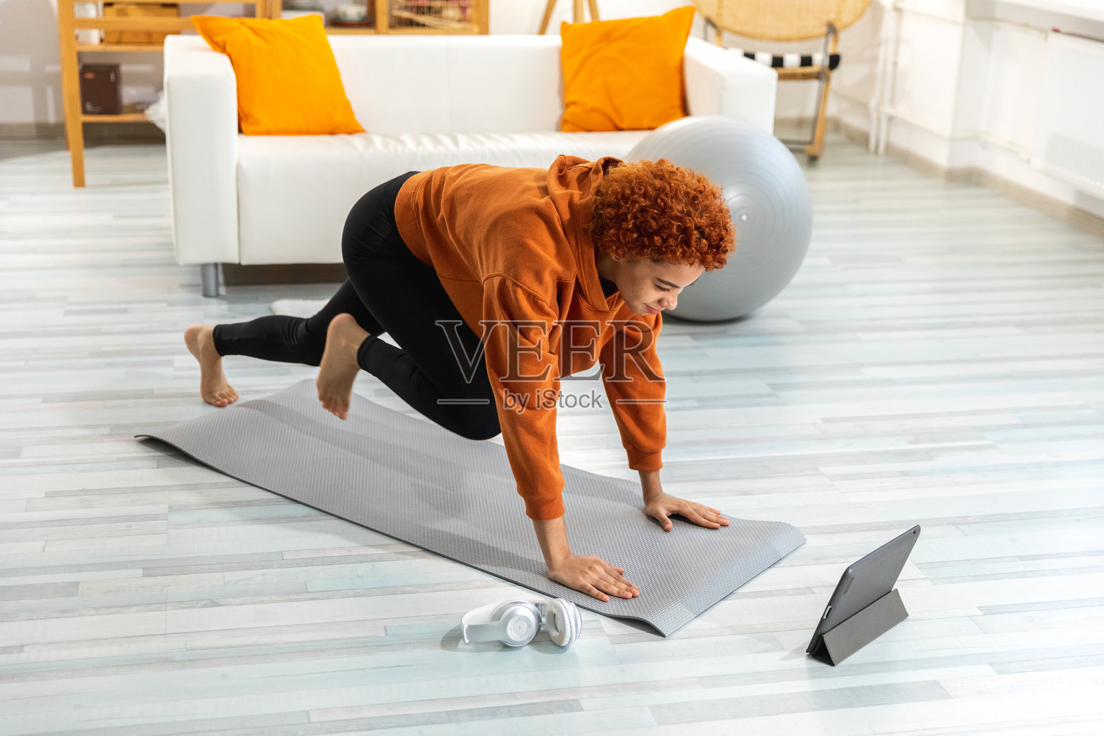 健身锻炼。年轻健康的非洲女孩在家里的瑜伽垫上进行运动锻炼。运动女性穿着运动服进行减肥训练。运动与健身。照片摄影图片