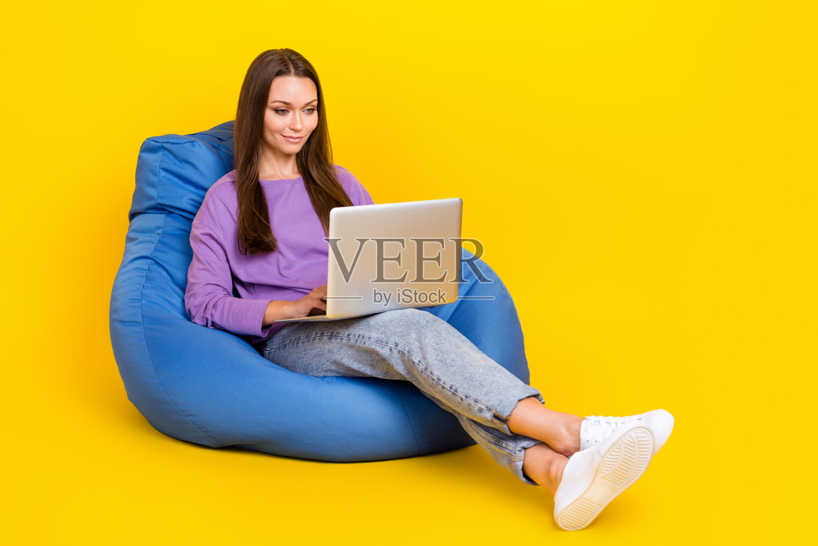 专注的女士坐在舒适的椅子上阅读新闻，与同事聊天，背景为黄色，空旷的空间。照片摄影图片