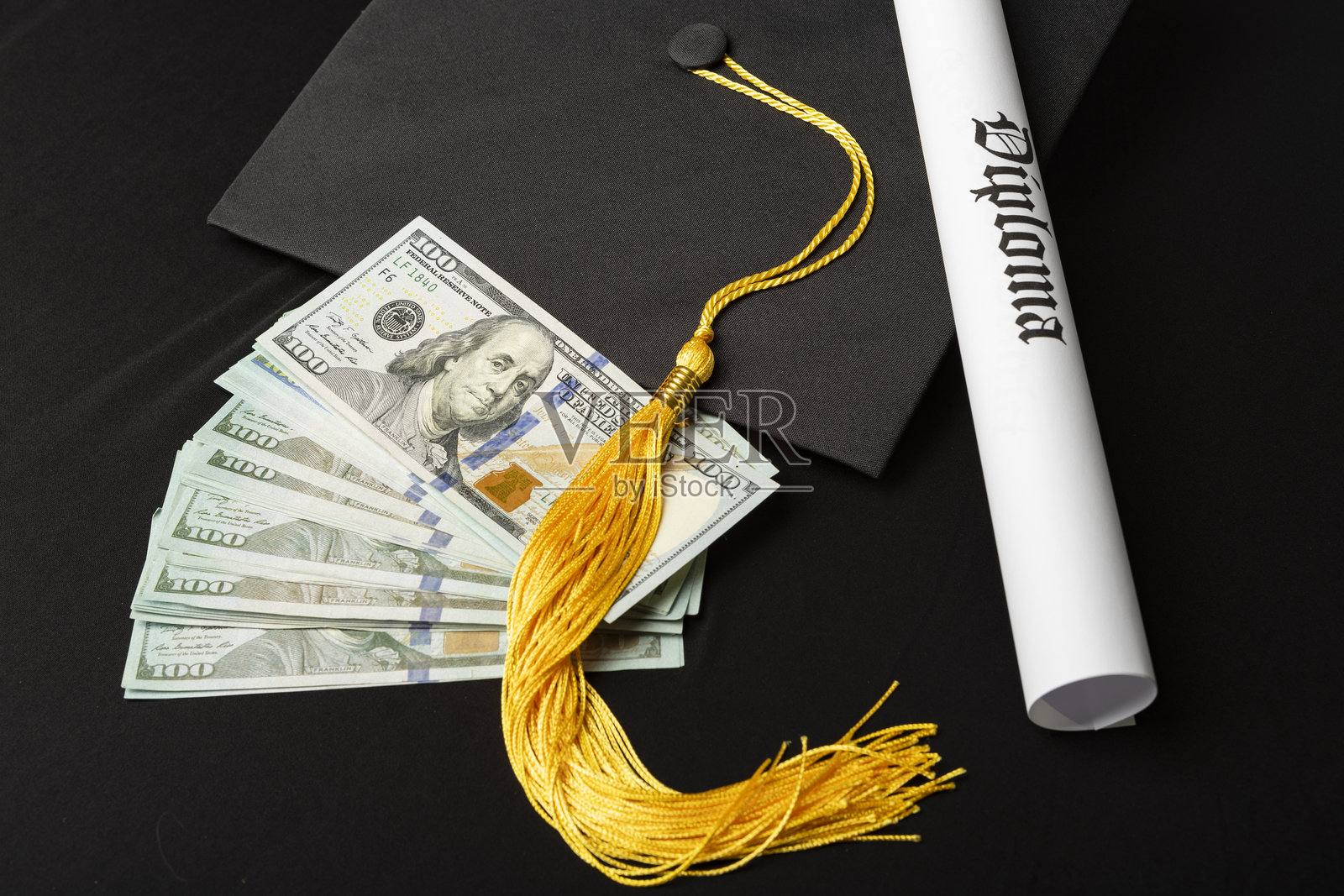 毕业帽和流苏，配有文凭和一叠现金照片摄影图片