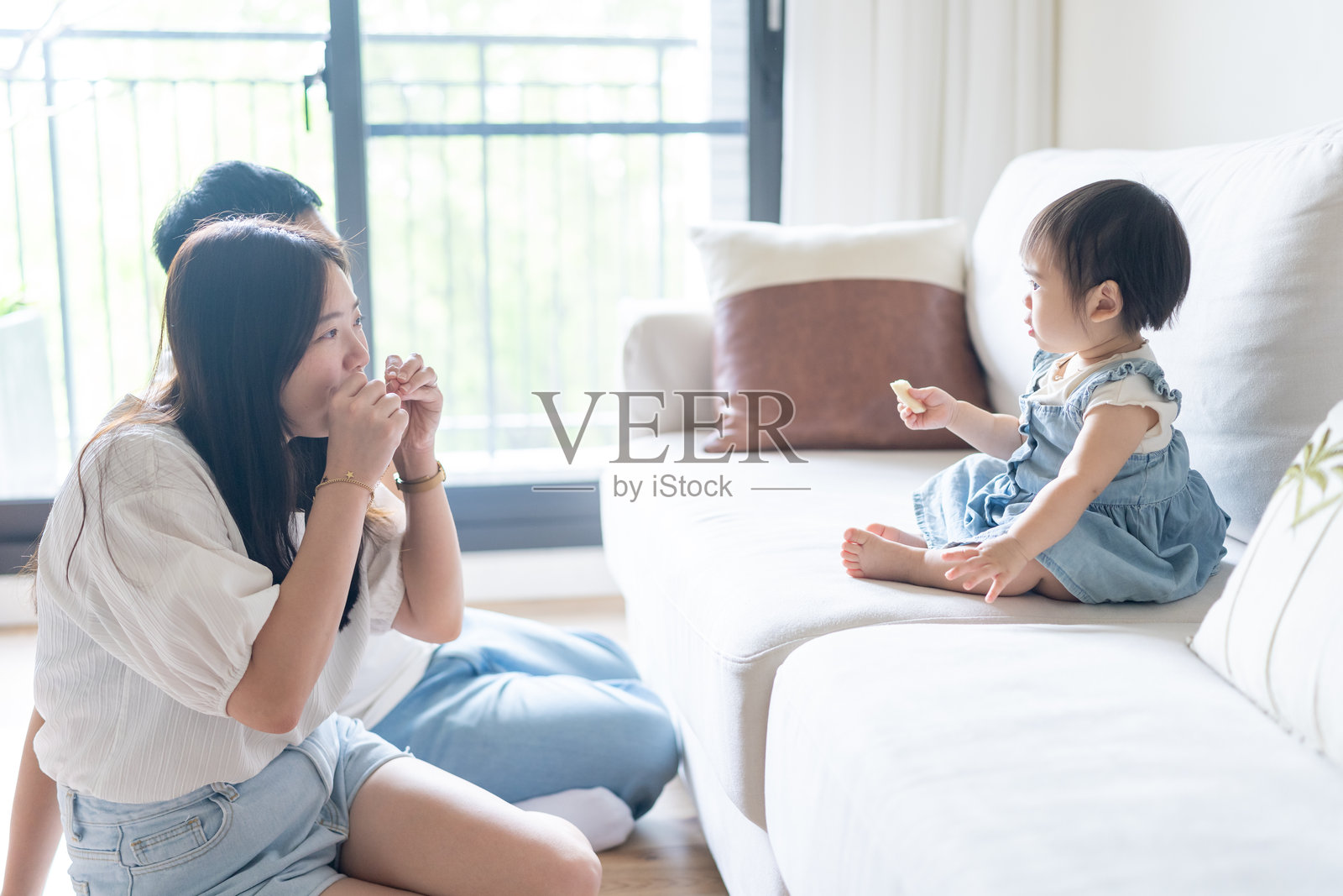 一名1岁的台湾女孩在台中市一栋高层公寓的房间里，和她的父母（20多岁的男女）快乐地玩耍。照片摄影图片