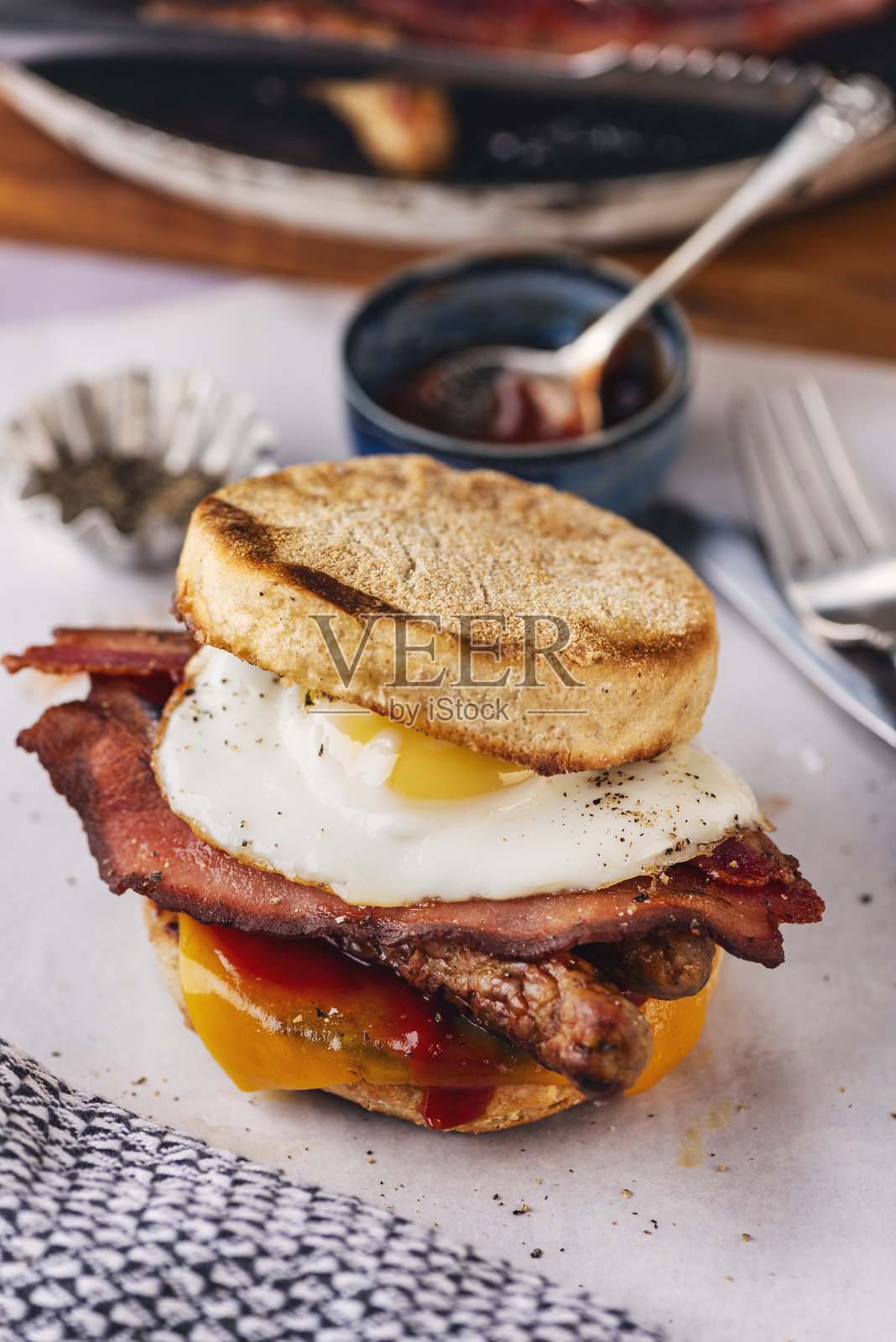 英式松饼配煎蛋、香肠、培根和融化的奶酪。照片摄影图片