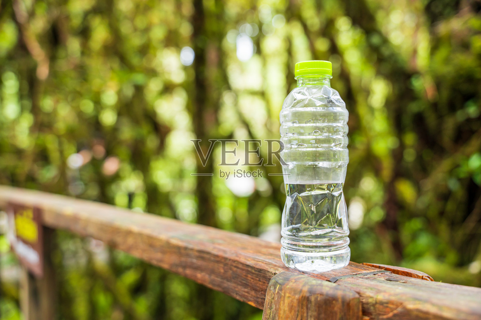 木桌上的水瓶，背景是模糊的绿色自然景色照片摄影图片