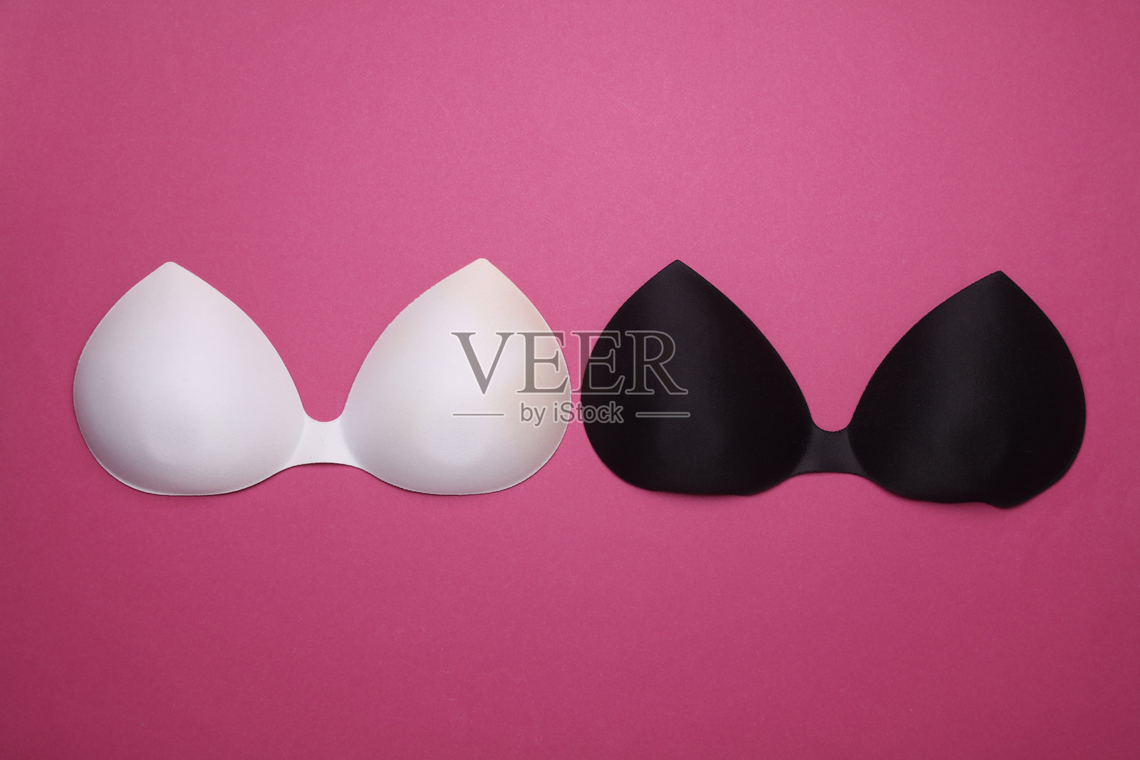 粉色背景上的黑白隐形胸罩。俯视图照片摄影图片