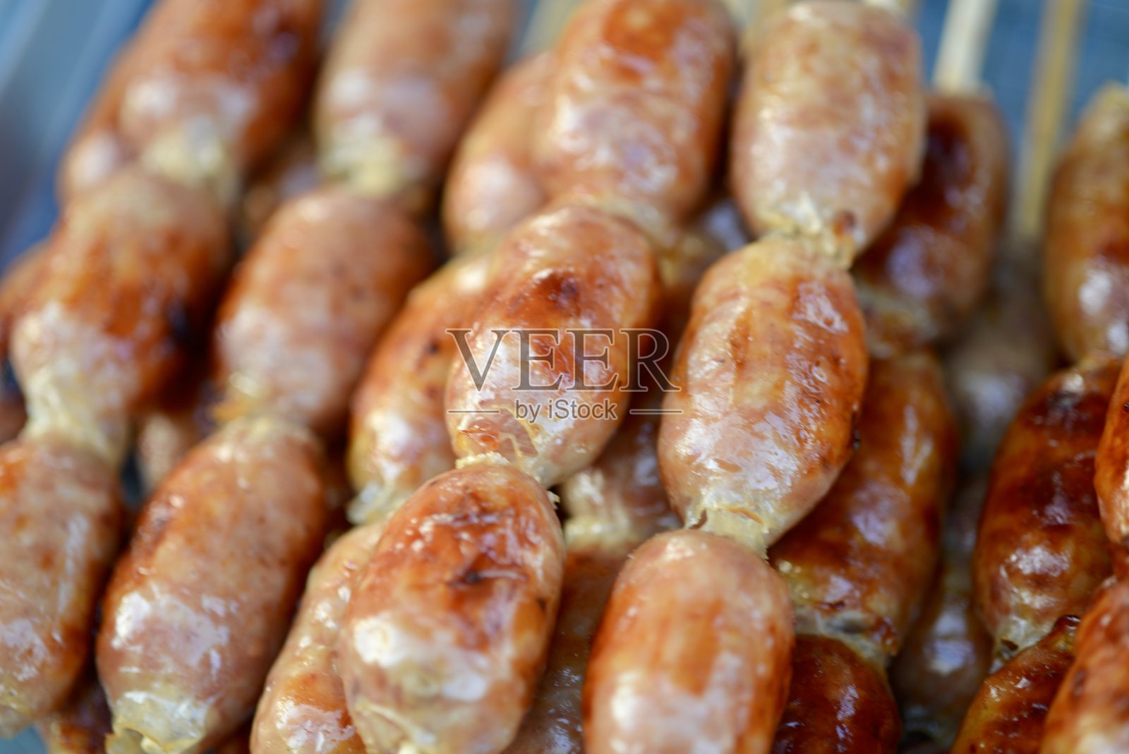一张宏观特写，展示了伊桑香肠，这是一道具有独特风味的传统泰国菜，正放在烤架上烤制。照片摄影图片