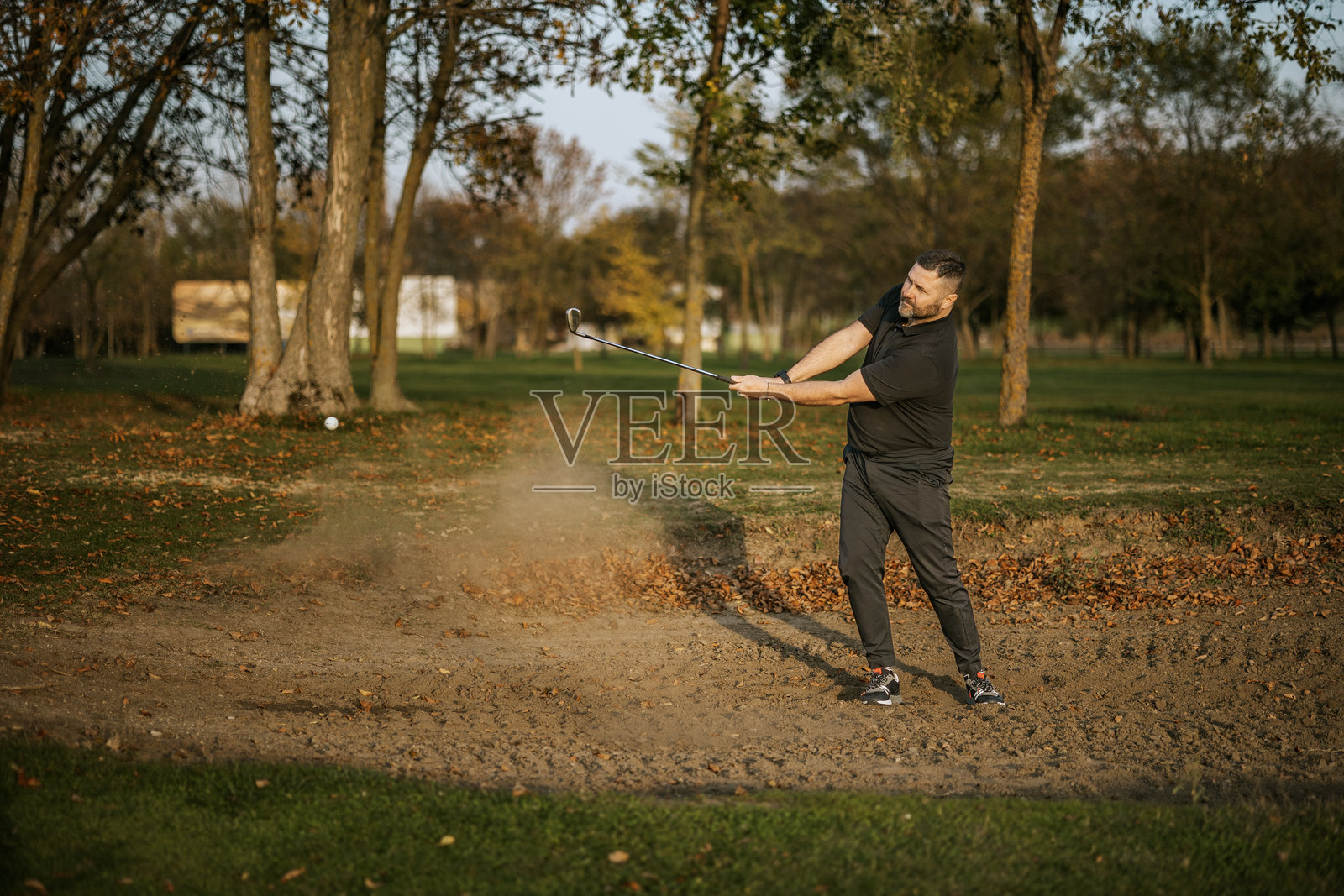 男子在沙坑中击球打高尔夫球照片摄影图片