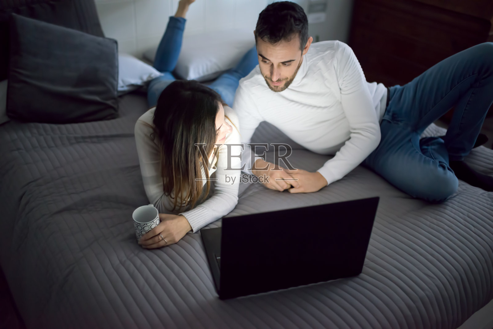 年轻情侣在床上夜晚用笔记本电脑观看电影照片摄影图片