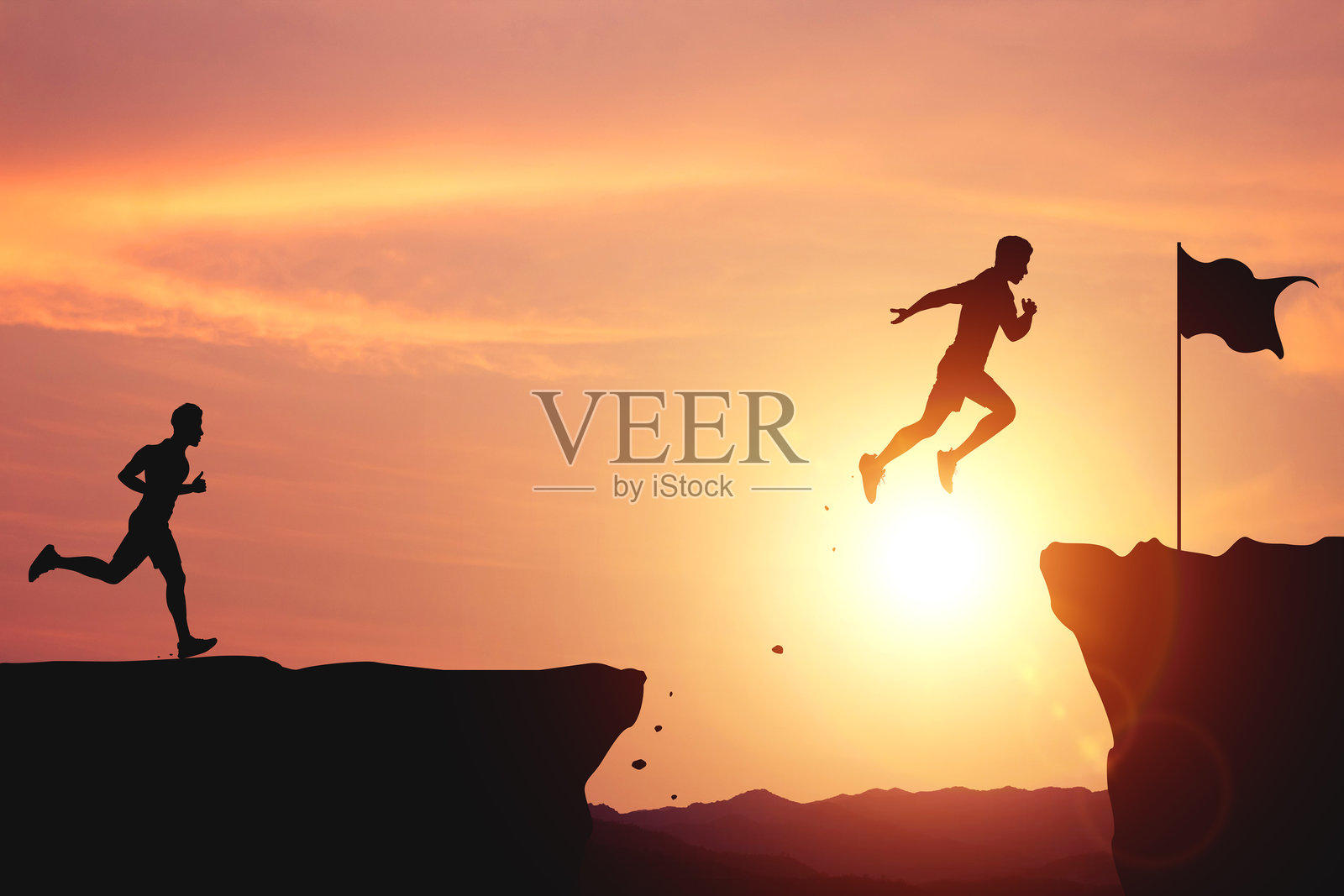 努力与成功的承诺。两名男子在阳光明媚的天空下跳过悬崖，以到达山顶的终点线。照片摄影图片