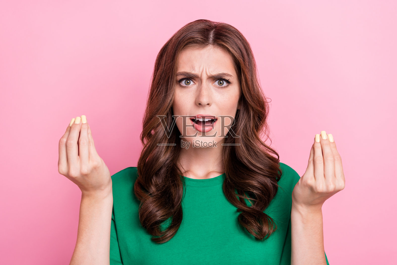 不满的愤怒漂亮女人在粉色背景下伸出手指询问为什么失去现金，破产，心情不好。照片摄影图片