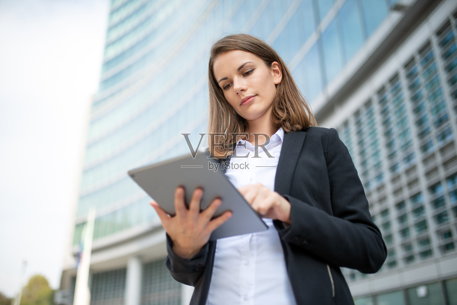 女商人在办公大楼前使用数字平板电脑照片摄影图片