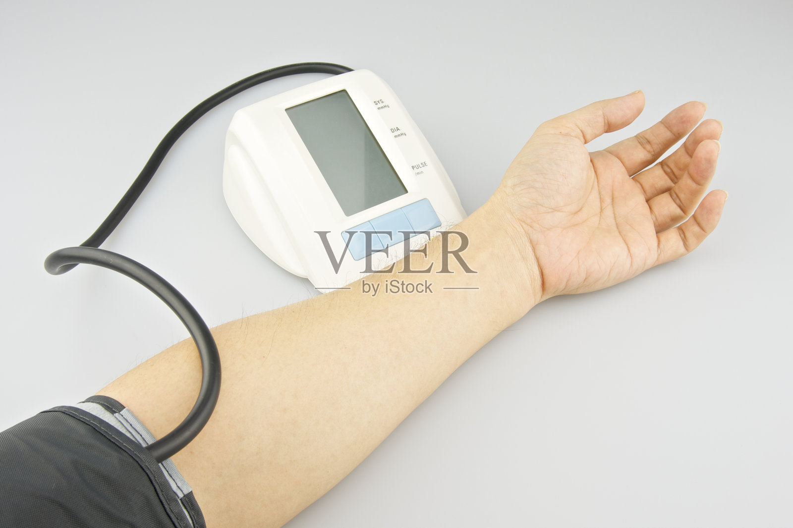 男子手持血压计，背景为灰色照片摄影图片