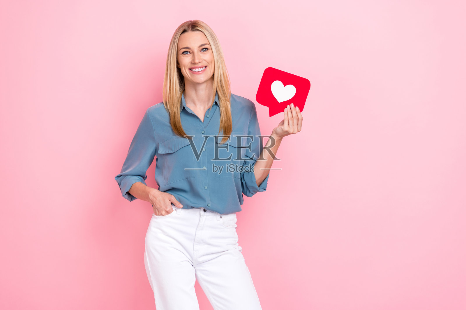 成熟成功的博客机构老板，金发，手持红色纸张状通知符号，自信地站在明亮的粉色背景前。照片摄影图片