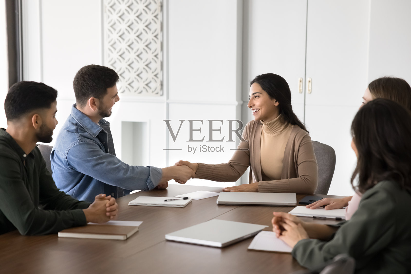 快乐成功的西班牙裔女性公司领导人与人握手照片摄影图片