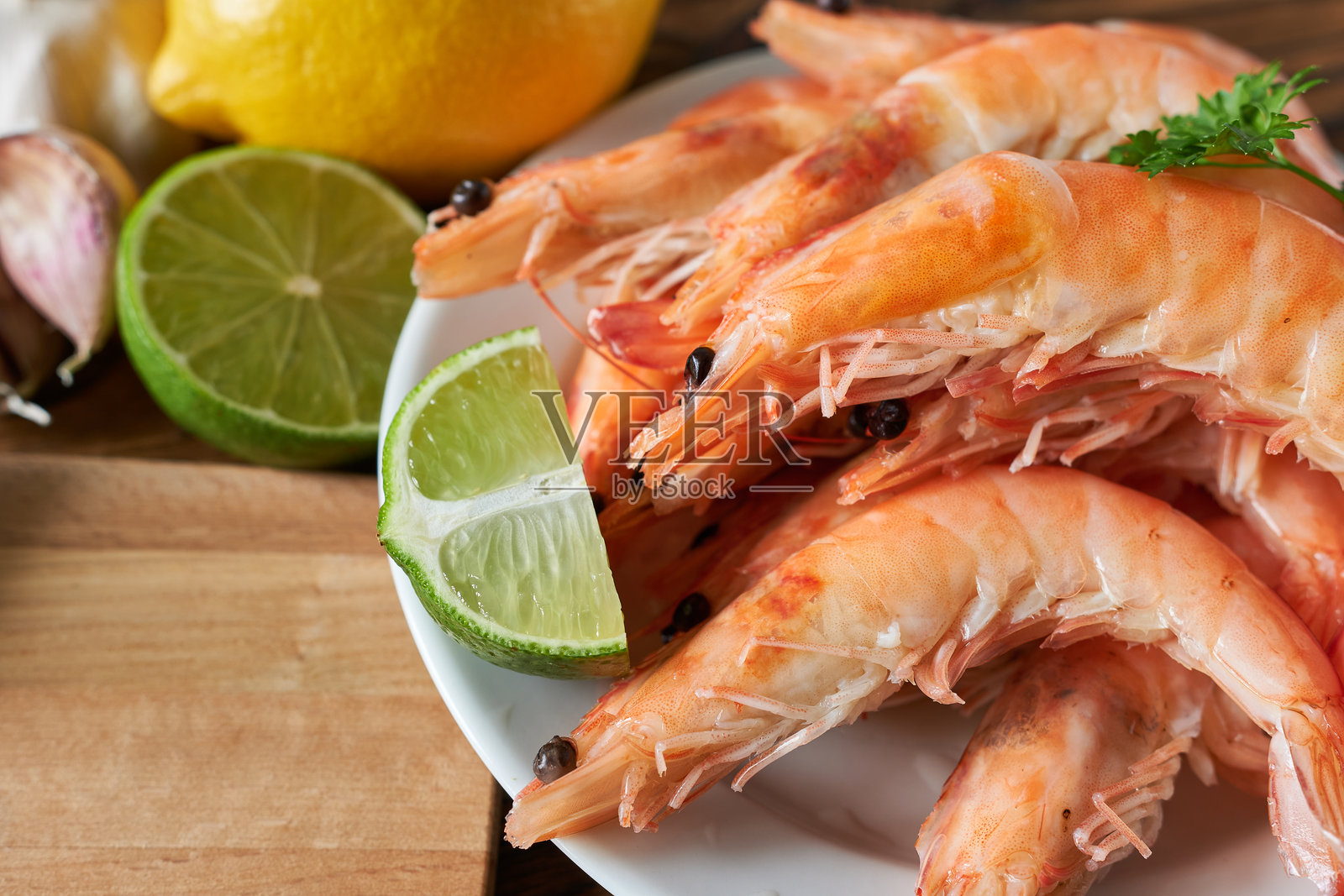 白盘上的煮虎虾，配有柠檬和大蒜照片摄影图片
