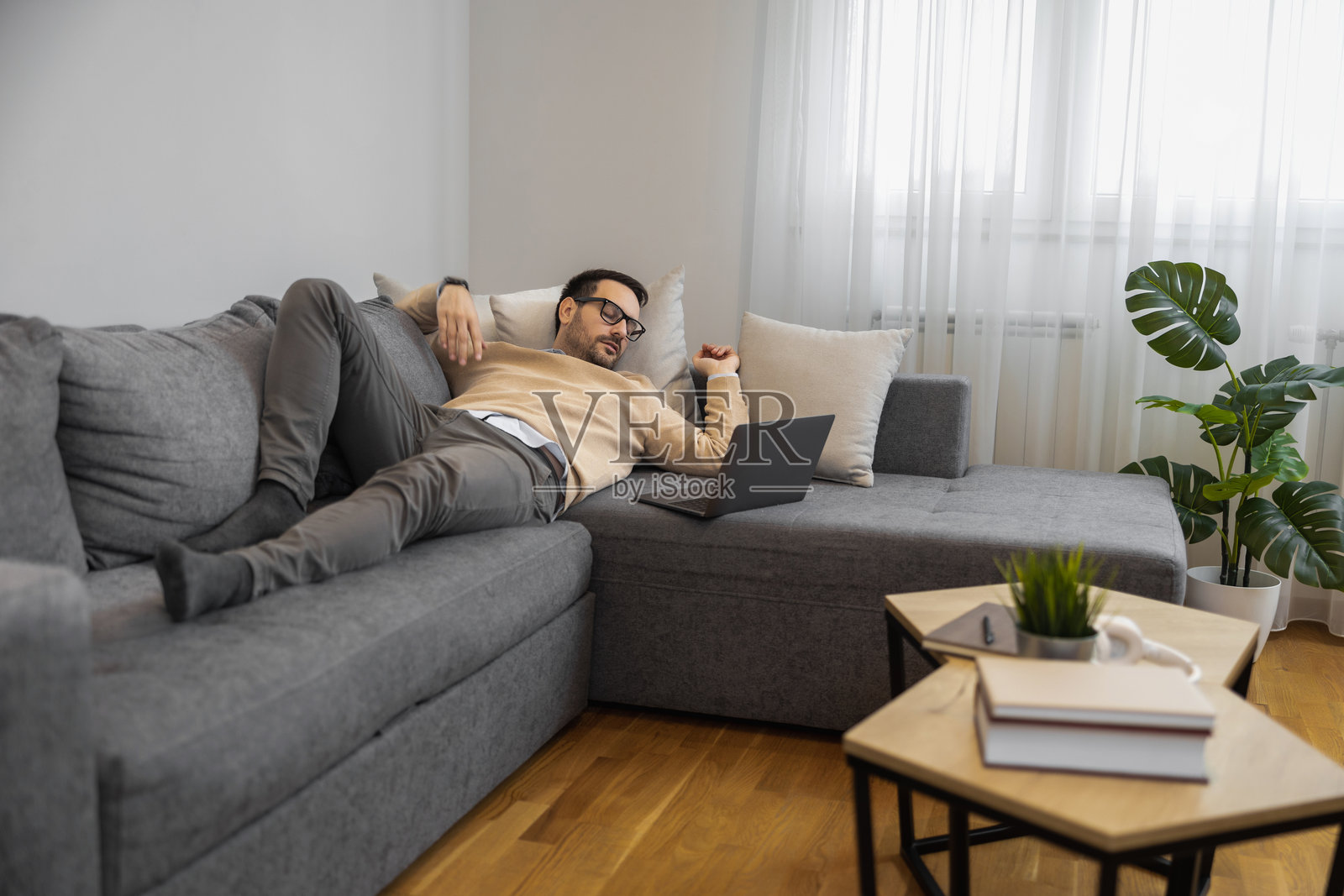 男人在家中悠闲地坐在沙发上使用笔记本电脑照片摄影图片