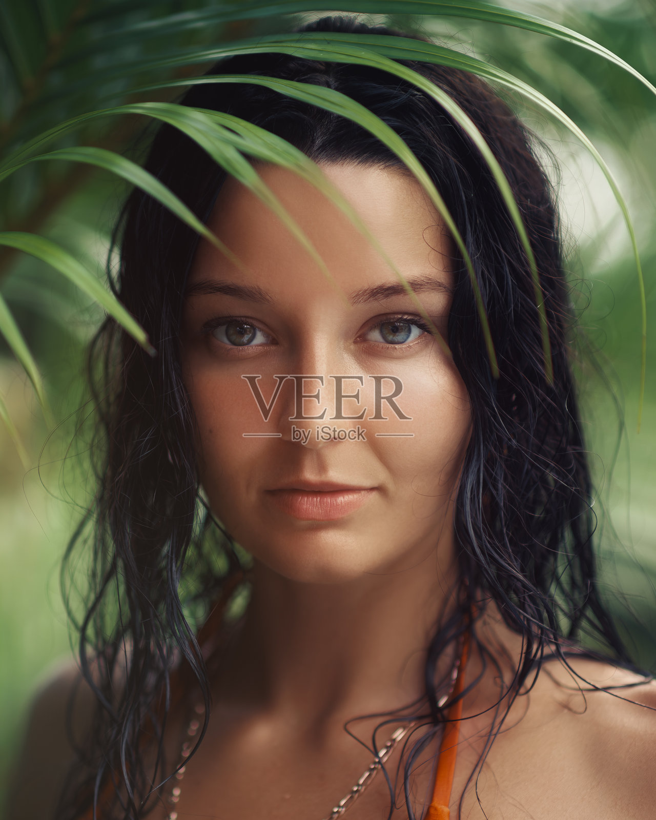 热带环境中，湿发女子的特写，周围环绕着郁郁葱葱的植物。照片摄影图片