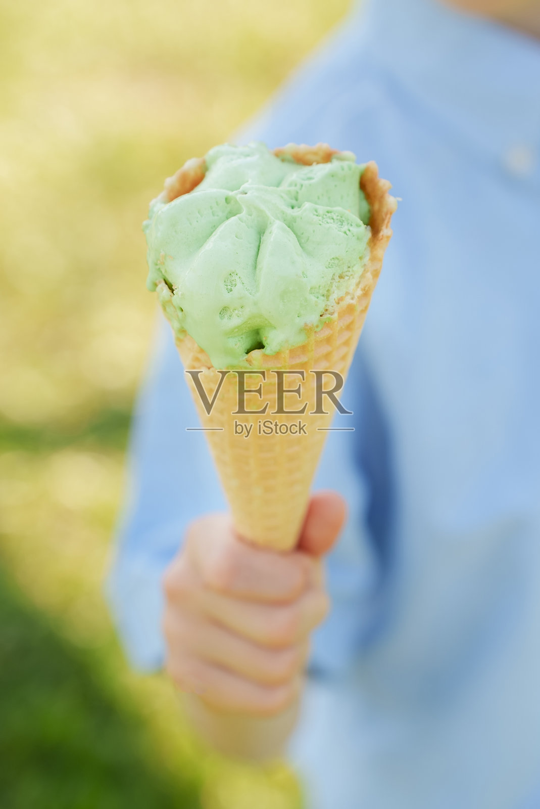 孩子手中拿着美丽的华夫筒冰淇淋，在阳光明媚的夏日里。炎热夏天的清爽享受，放松在大自然中。竖版照片摄影图片