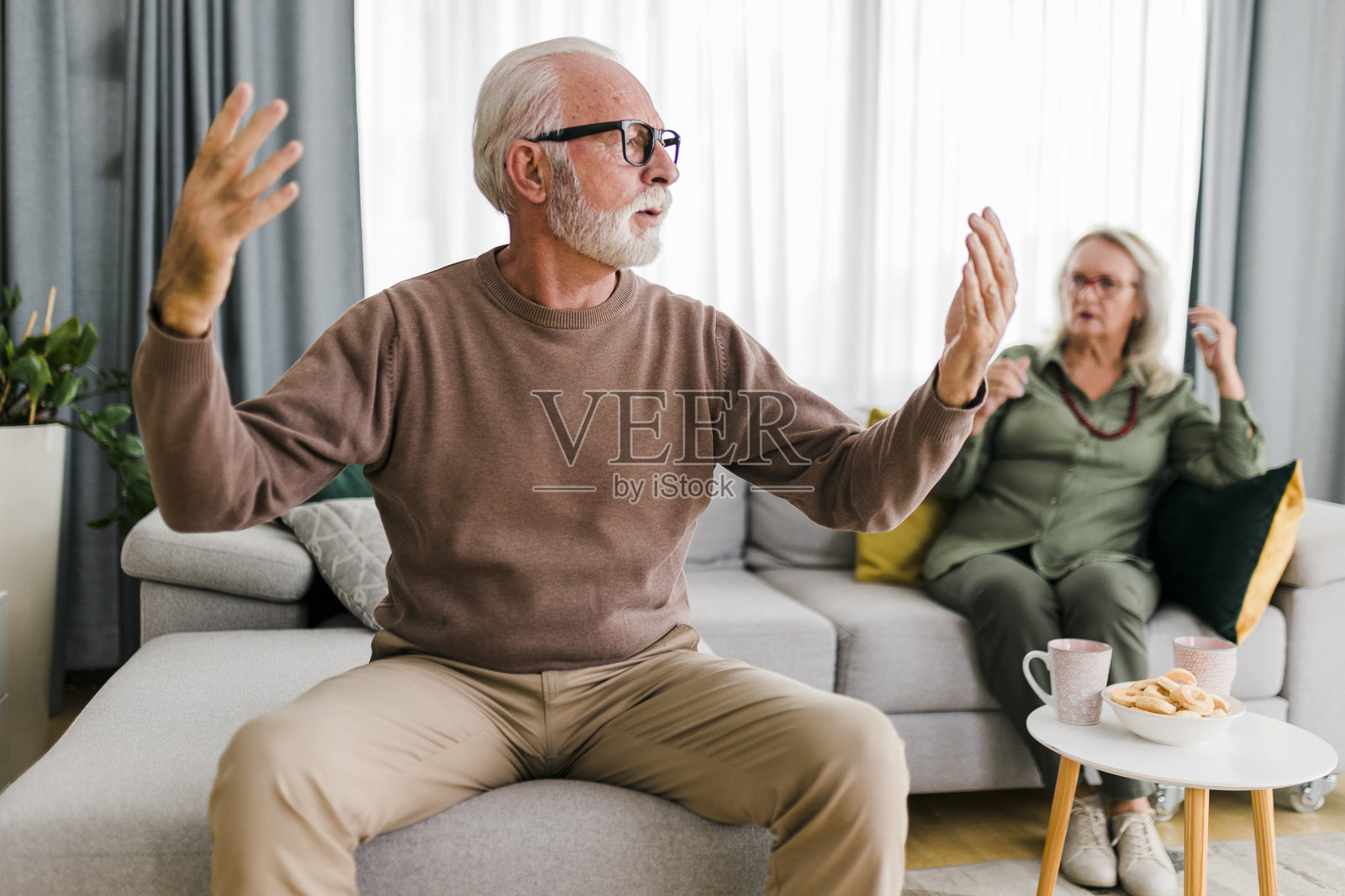 一对年长的异性情侣在家里的沙发上争吵。照片摄影图片