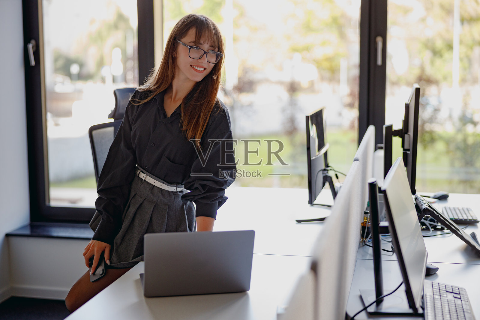 一位在现代办公室环境中工作的职业女性，周围有多台电脑。照片摄影图片