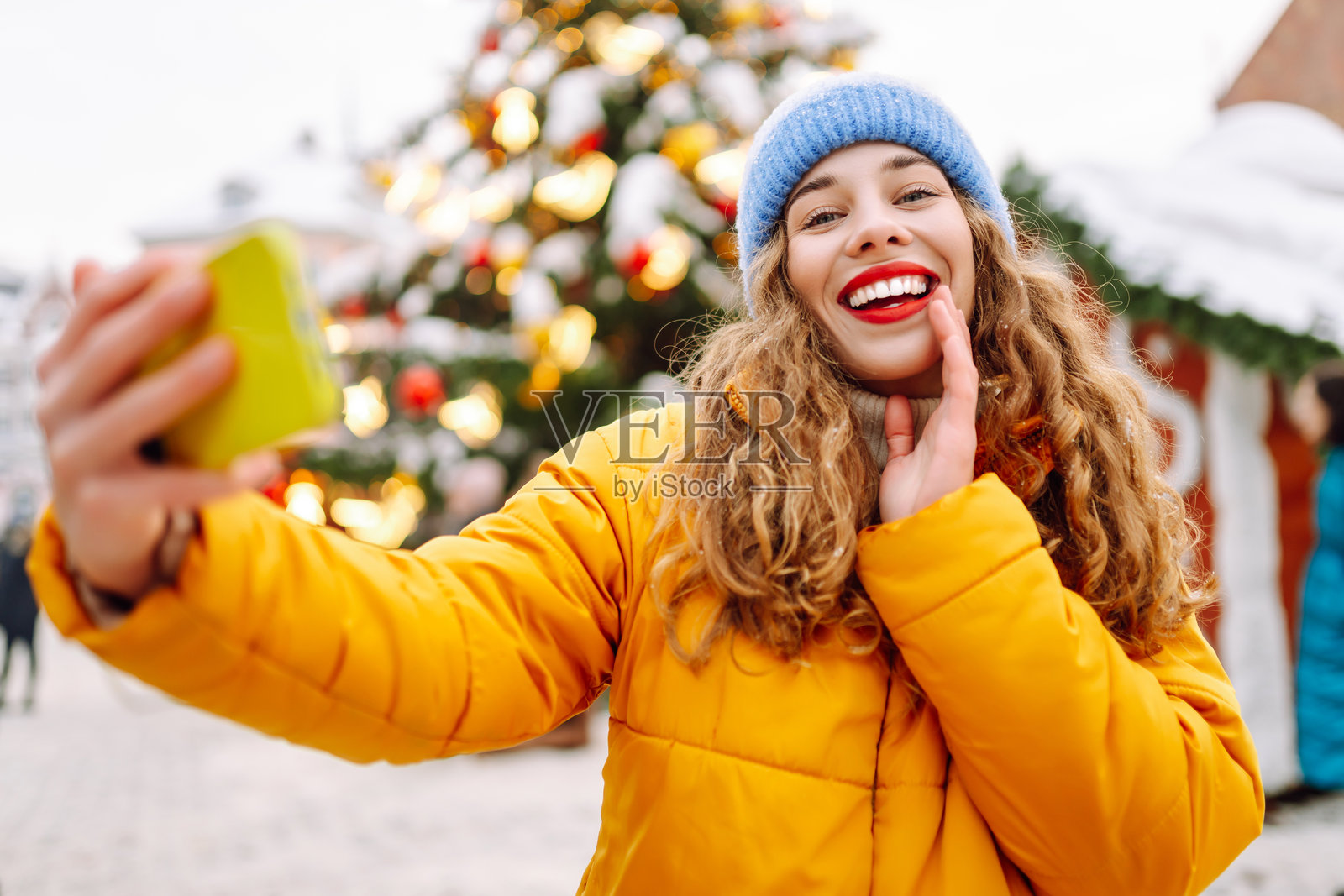 快乐的女性穿着冬季服装在城市街道的圣诞市场自拍。照片摄影图片