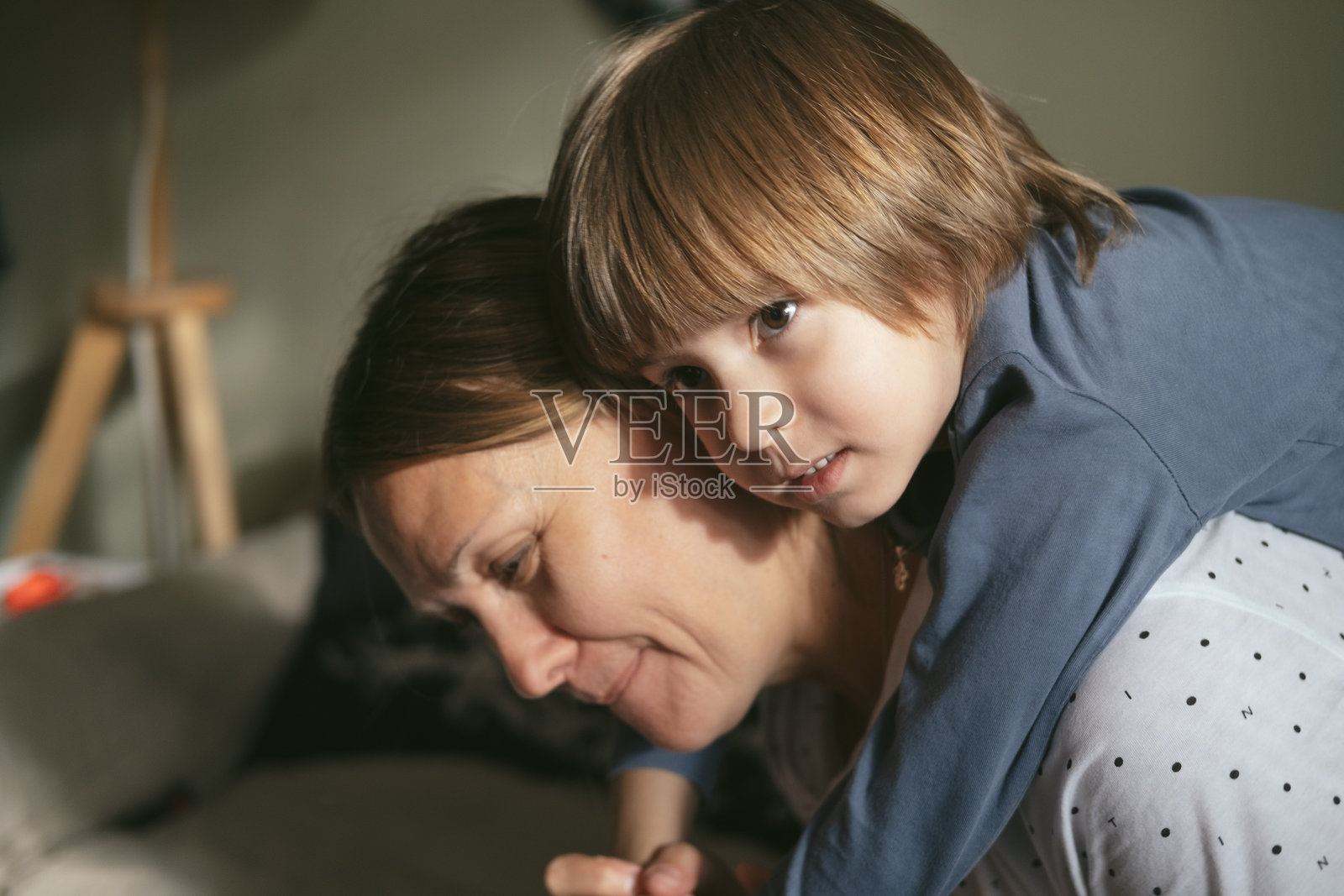 母亲或祖母与她的小儿子或孙子在家中拥抱并一起玩耍。照片摄影图片