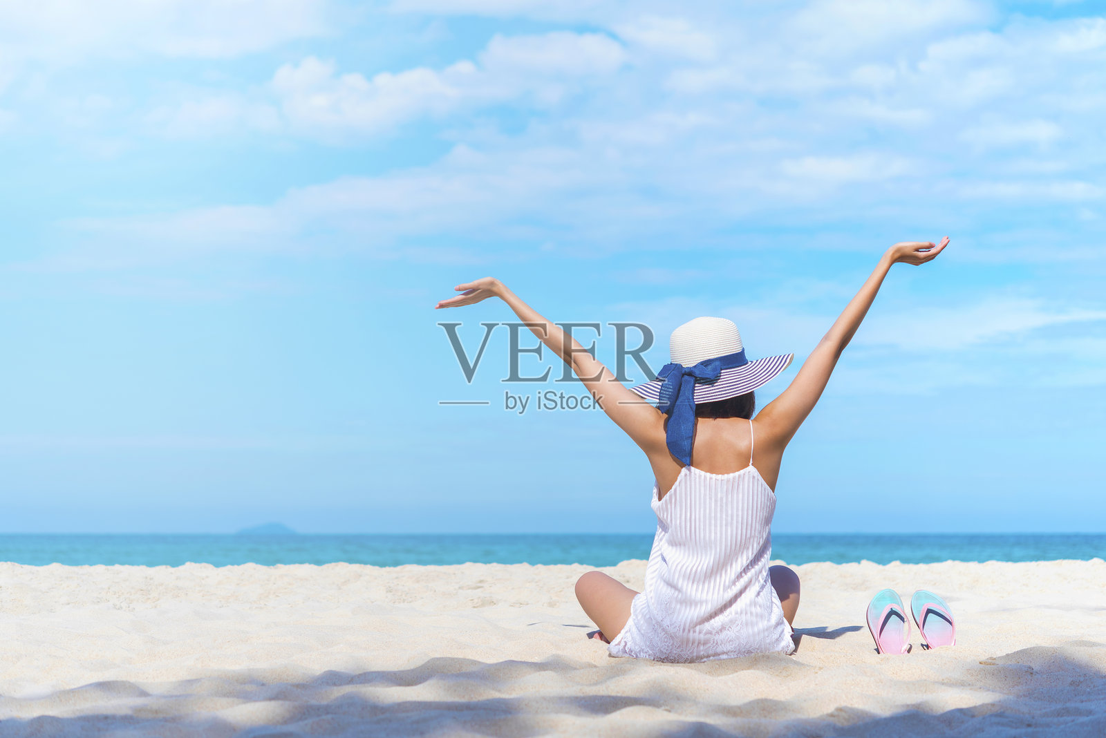 背影的女人坐在海滩上，天空为背景照片摄影图片