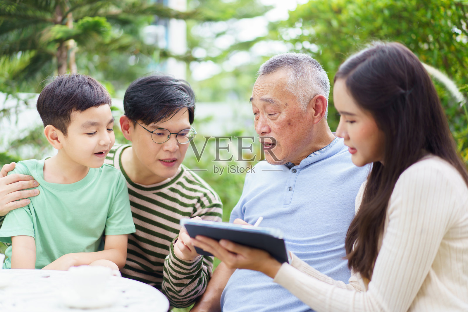 多代亚洲家庭在后院花园中一起放松。照片摄影图片