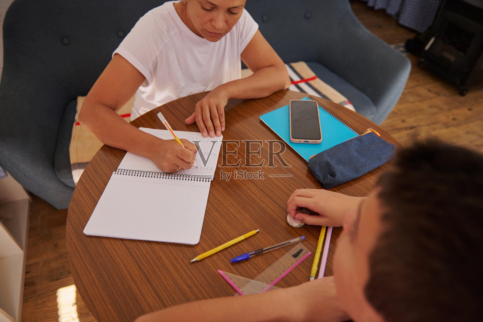 母亲在厨房桌子旁帮助孩子做作业照片摄影图片