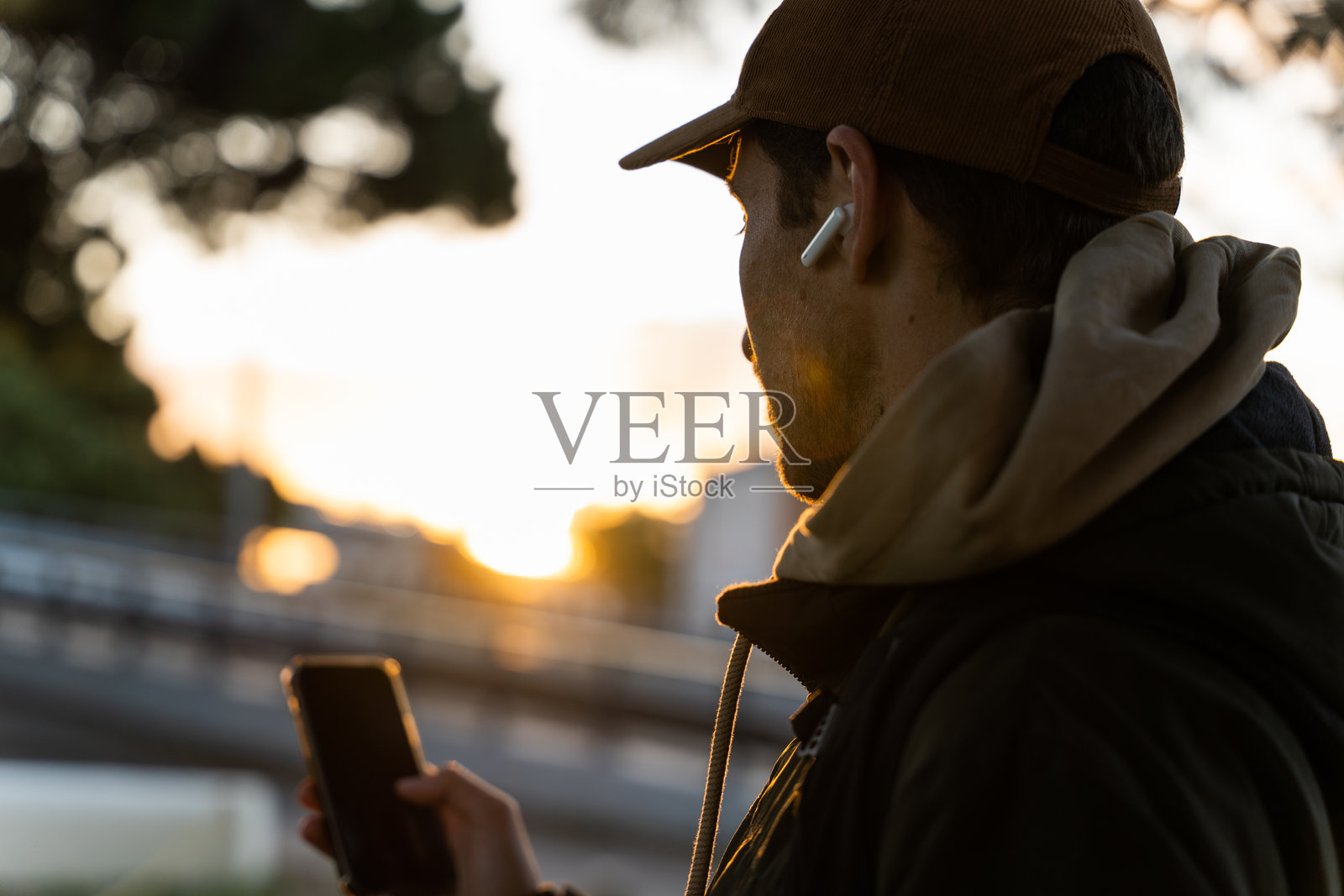 一个男人在下午走在城市里时看着他的手机照片摄影图片