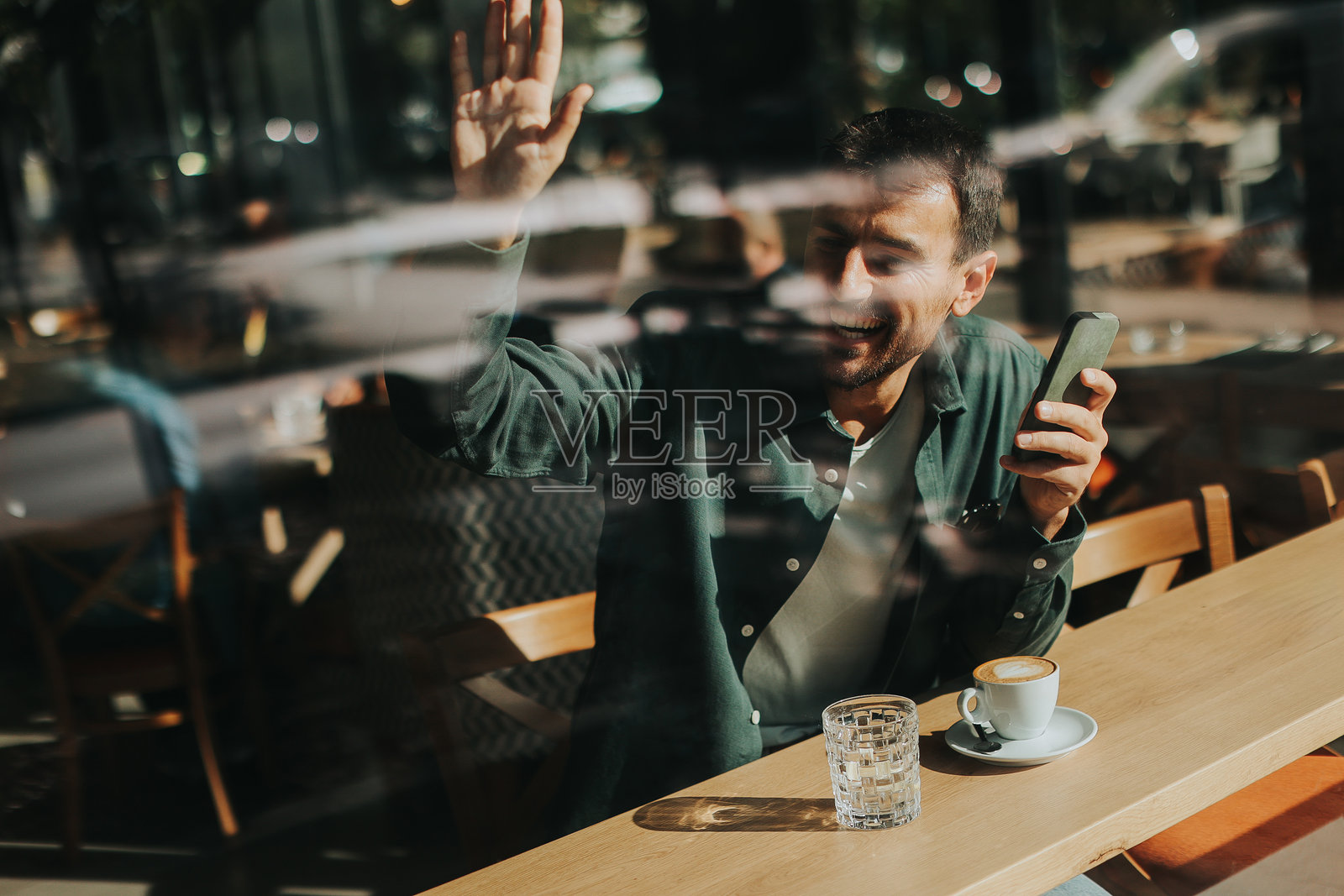 一个沉思的男人在阳光明媚的日子里，独自在舒适的咖啡馆里品味咖啡，静静地坐在窗边沉思。照片摄影图片