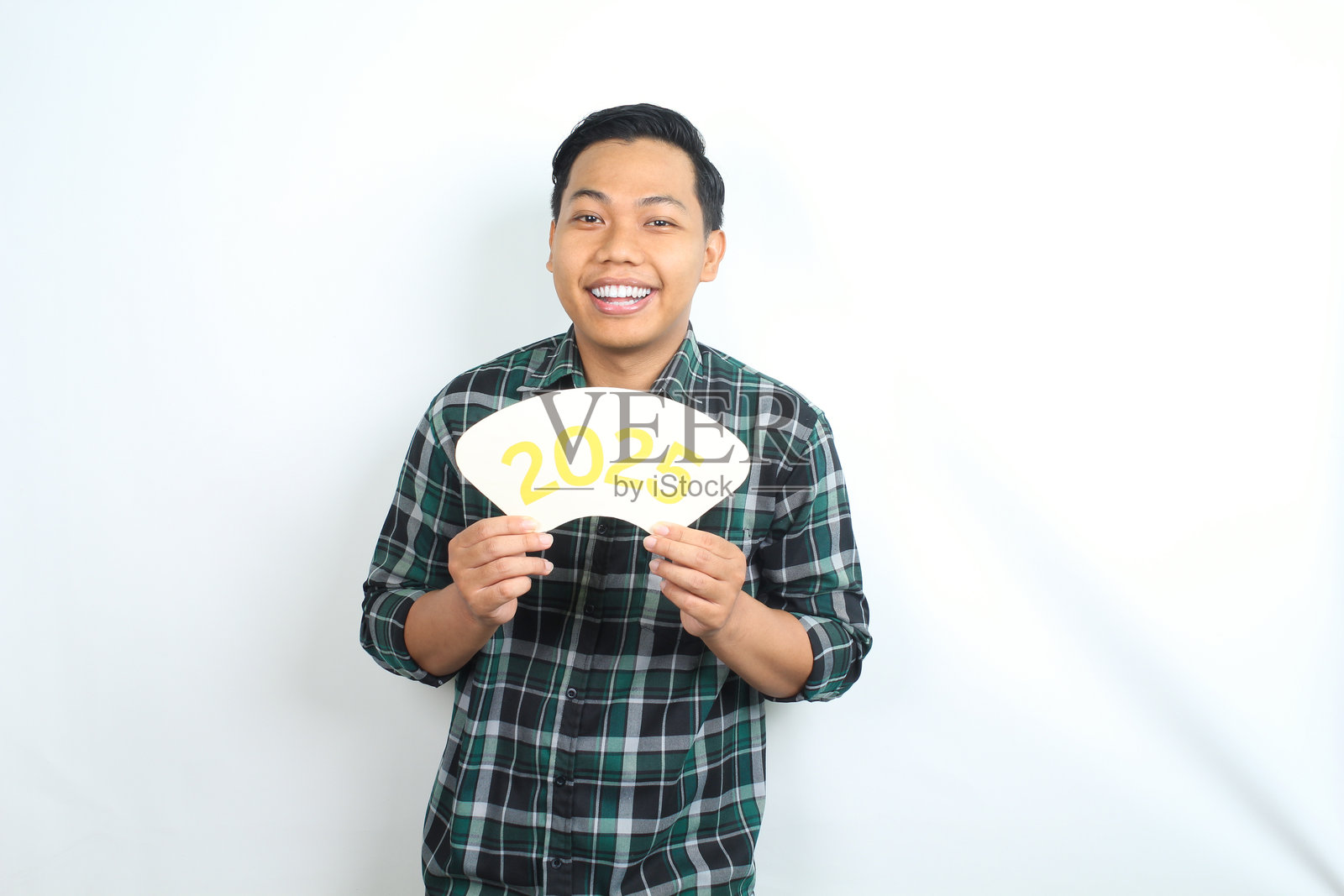 孤独的快乐亚洲男子穿着休闲服，庆祝新年前夕，手持2025卡片。照片摄影图片