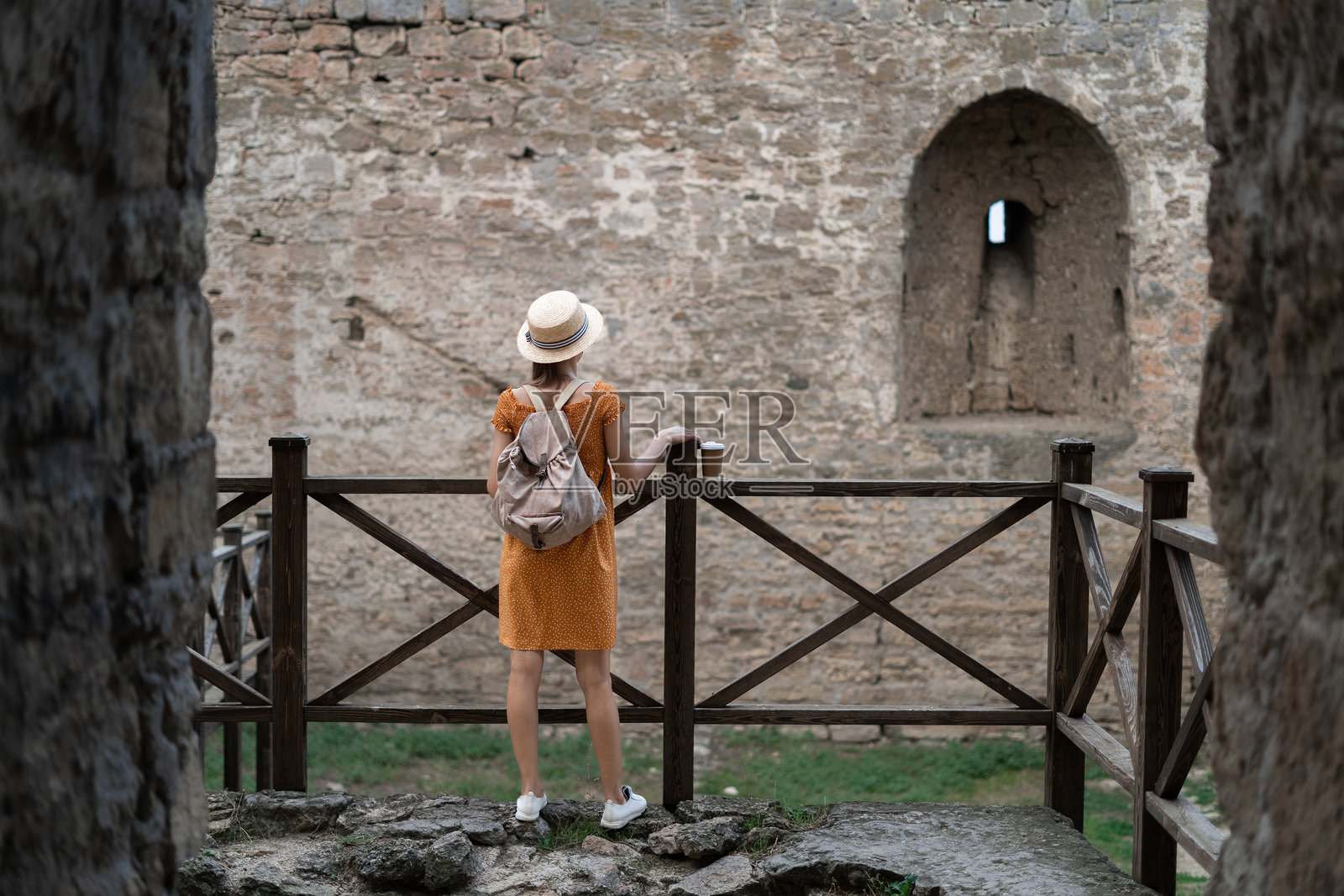 女游客参观古老的堡垒，凝视着古城墙照片摄影图片