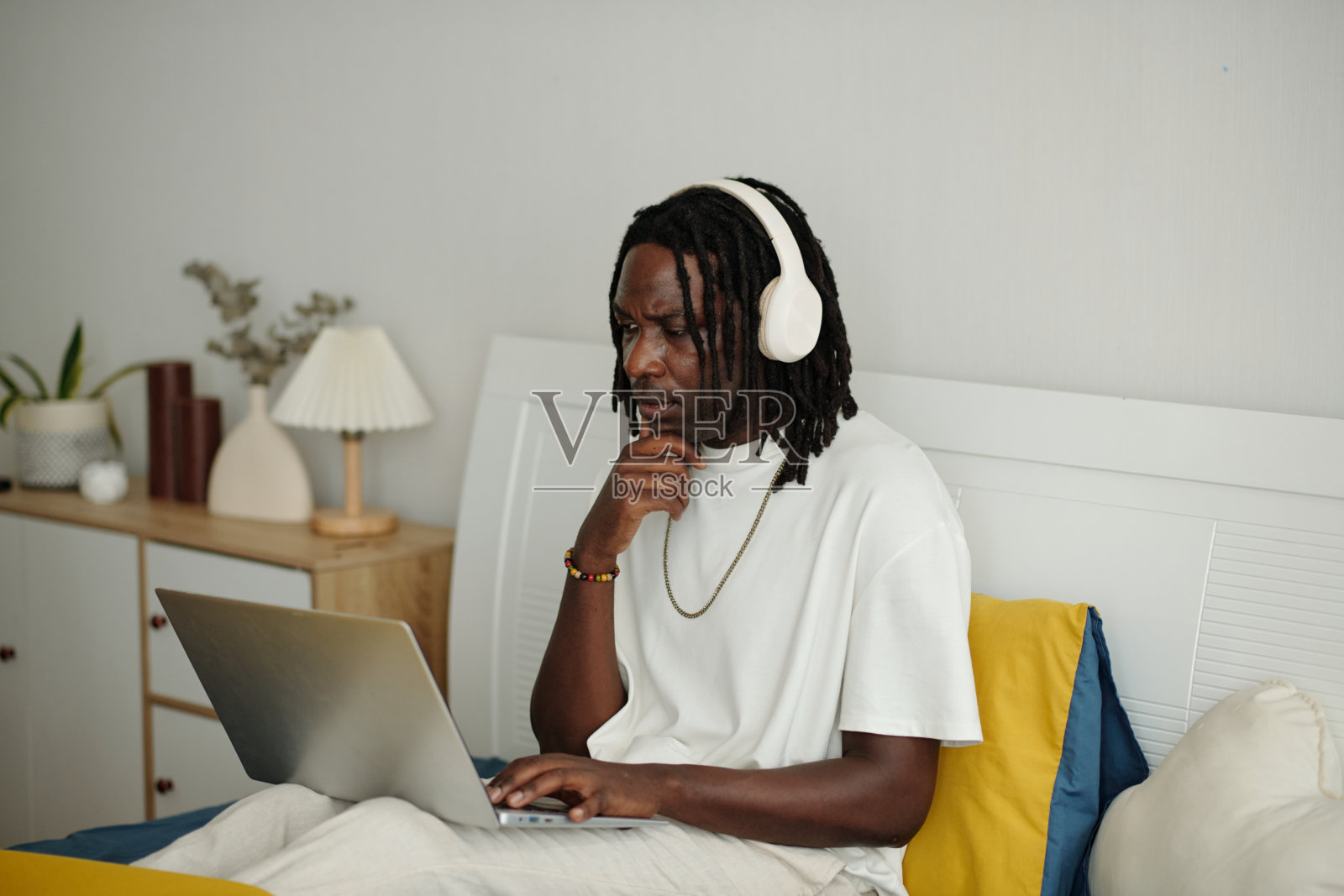 戴着耳机在笔记本电脑上工作的沉思者照片摄影图片