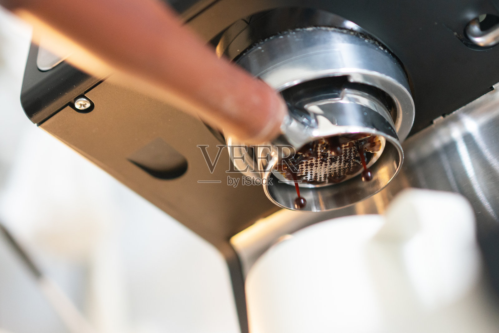 咖啡机的咖啡手柄特写，正在将浓缩咖啡注入玻璃杯中。照片摄影图片