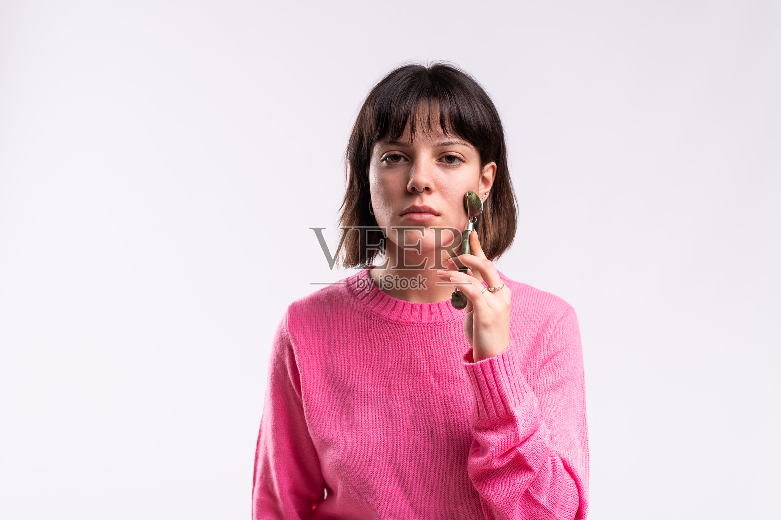 年轻女性使用玉石滚轮按摩面部，进行护肤程序照片摄影图片