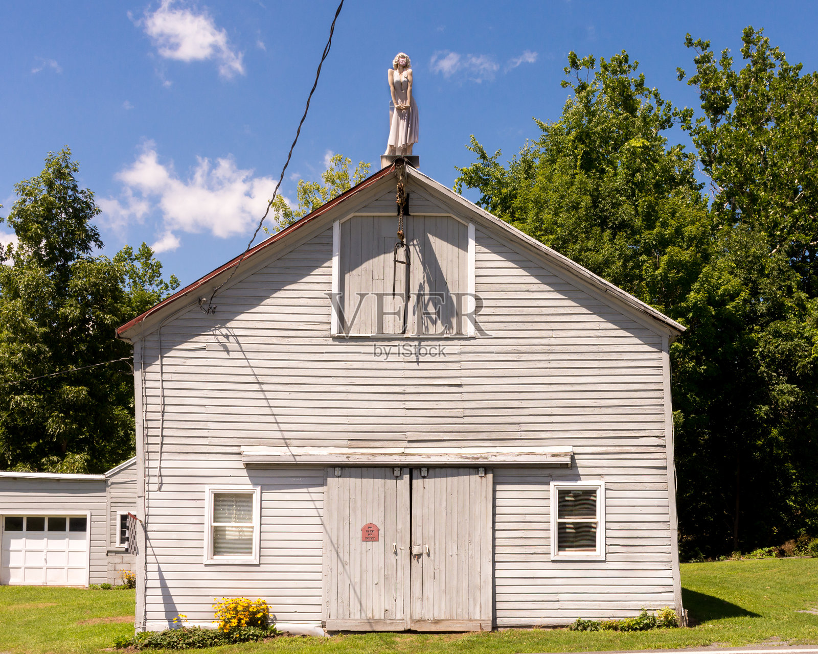 玛丽莲·梦露的模特在纽约伦斯勒县的谷仓顶部摆姿势，阳光明媚的夏日。照片摄影图片