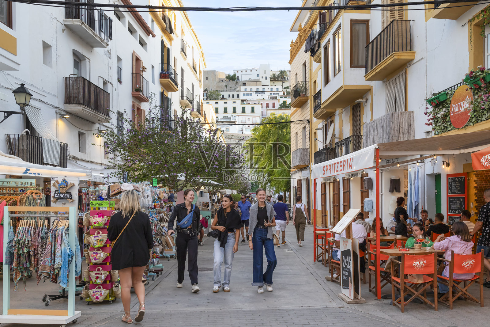人们在伊比萨镇中心的小商店和露台之间的温馨狭窄街道上漫步。照片摄影图片