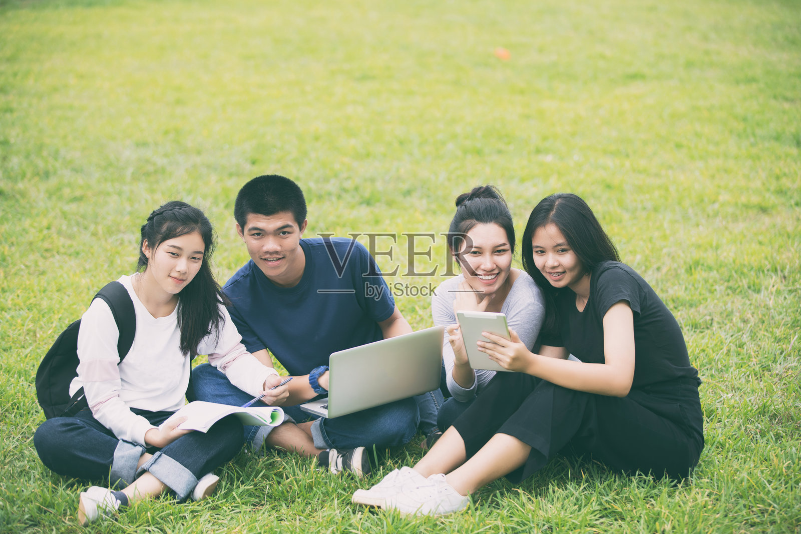 坐在草地上讨论技术的朋友的高角度视图照片摄影图片