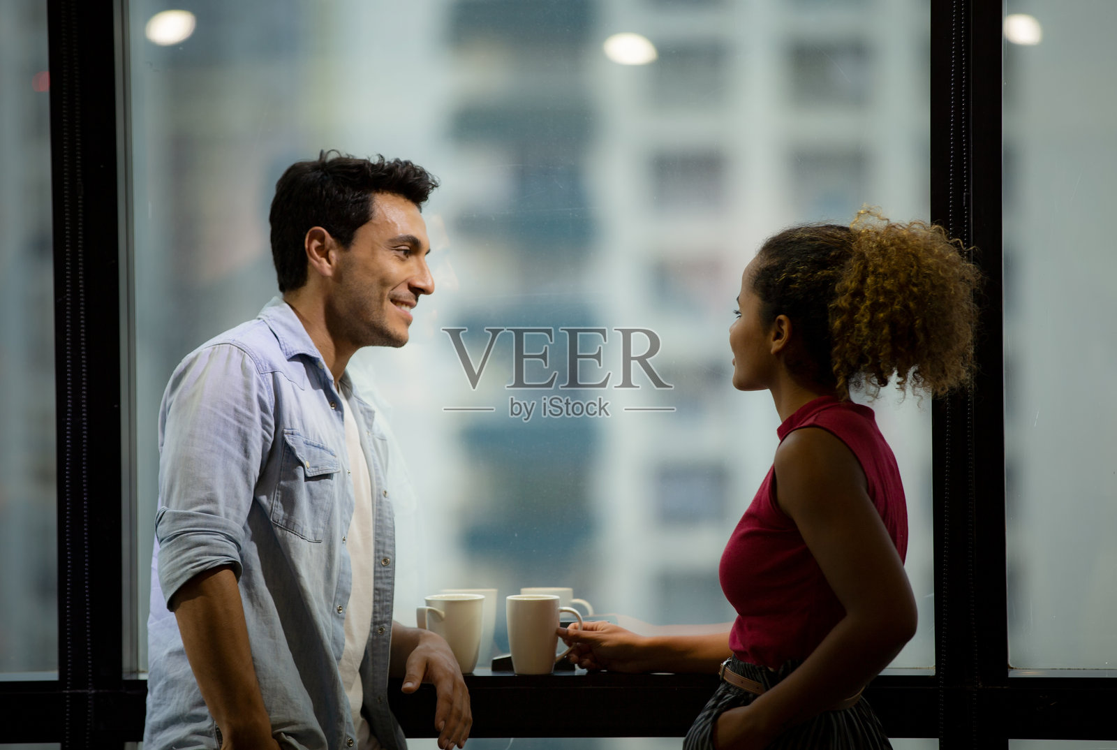 在办公室靠着窗户说话的同事的侧视图照片摄影图片