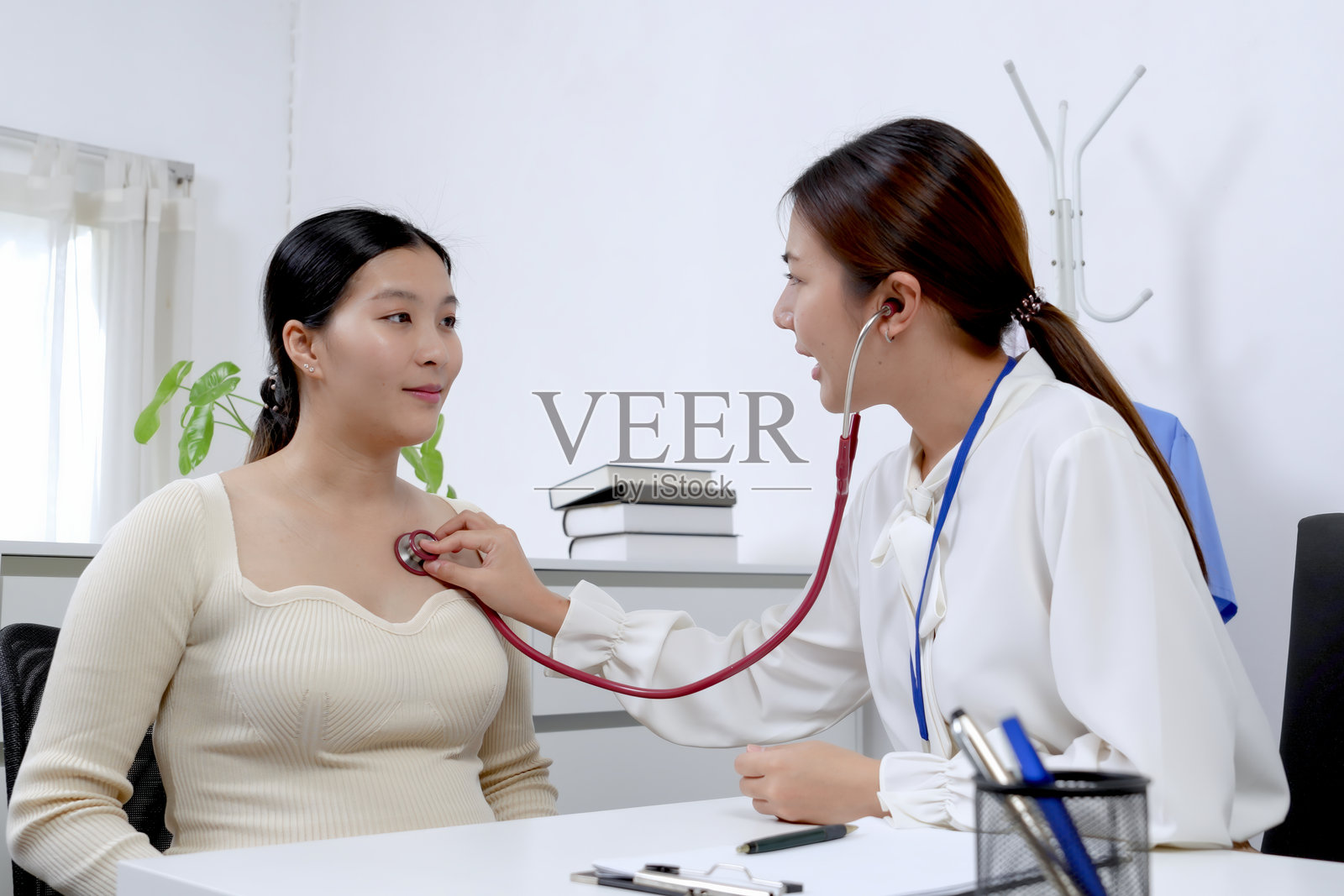 医生在产前咨询中使用听诊器检查孕妇的胸部，专注于监测心脏健康，确保母亲和未出生婴儿的健康状况。照片摄影图片