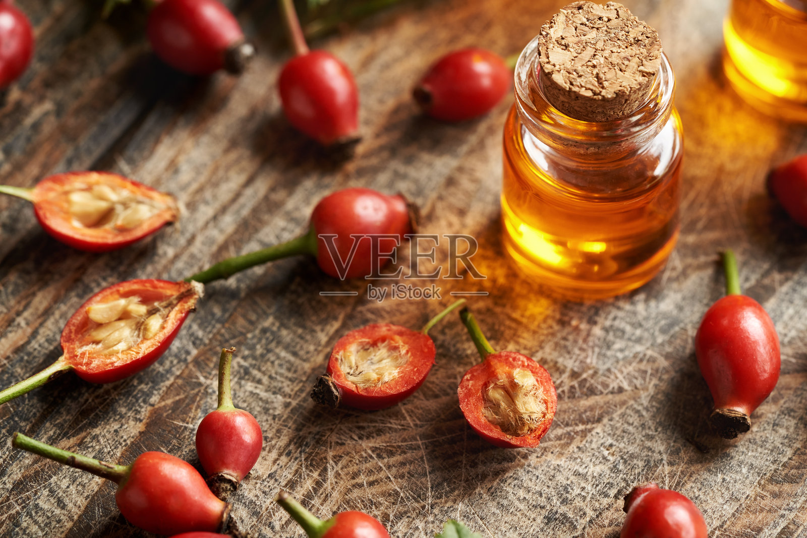 一瓶玫瑰果种子油和新鲜的玫瑰果在桌子上照片摄影图片