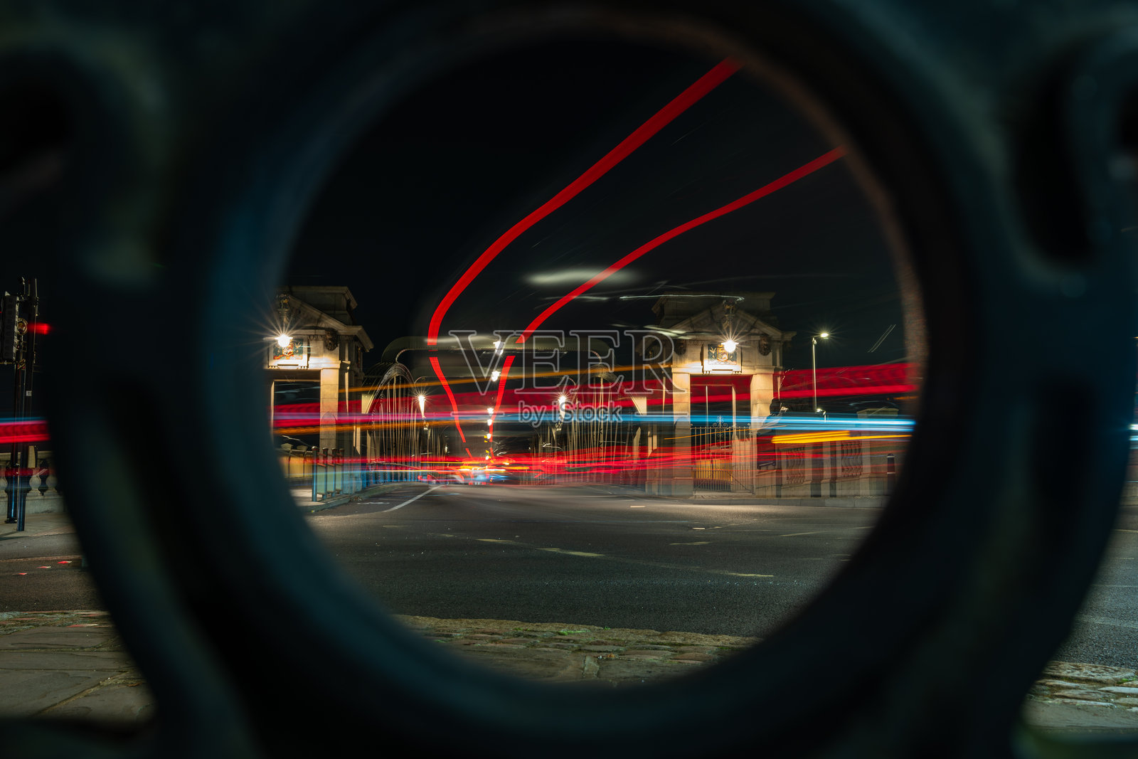 夜晚通过圆形孔洞看到的桥上汽车行驶的光轨照片摄影图片