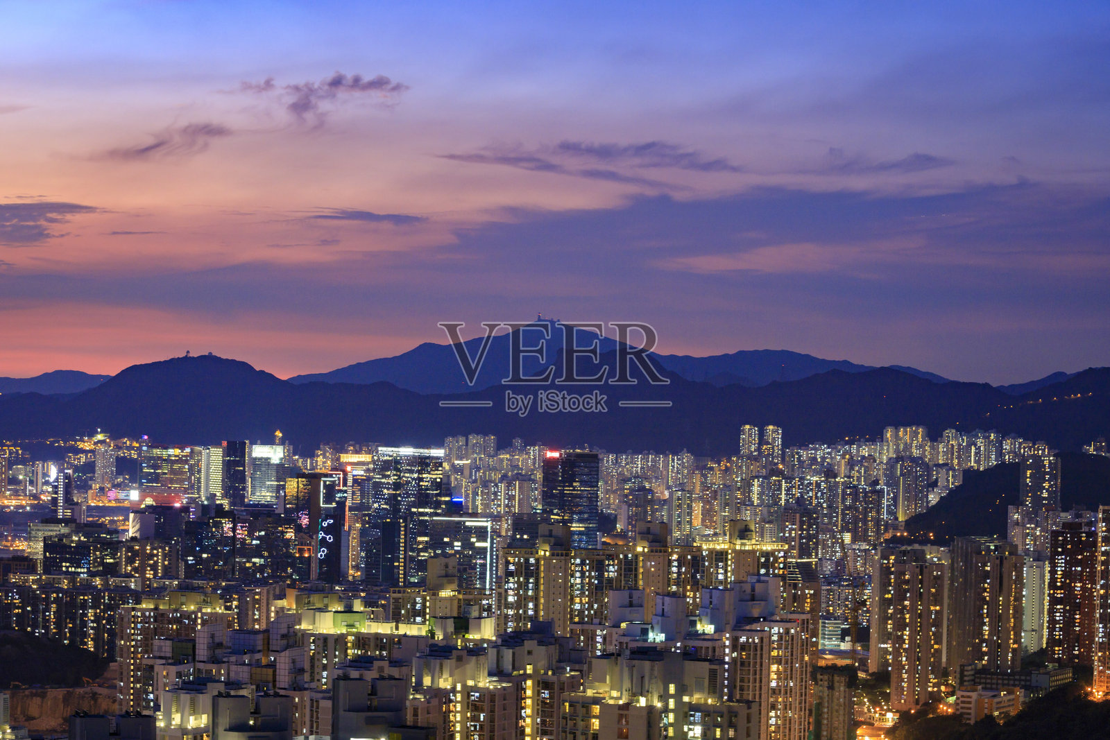 黄昏时分的生动城市景观，背景是香港的山脉，魔幻时刻。照片摄影图片