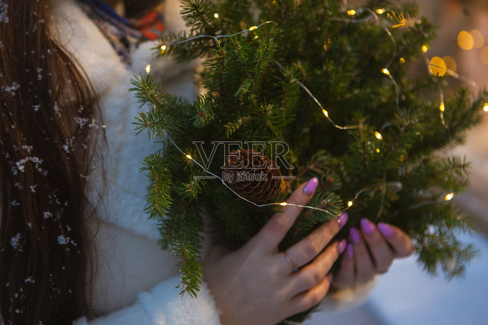 一位女性开心地手捧一棵小型装饰圣诞树。照片摄影图片